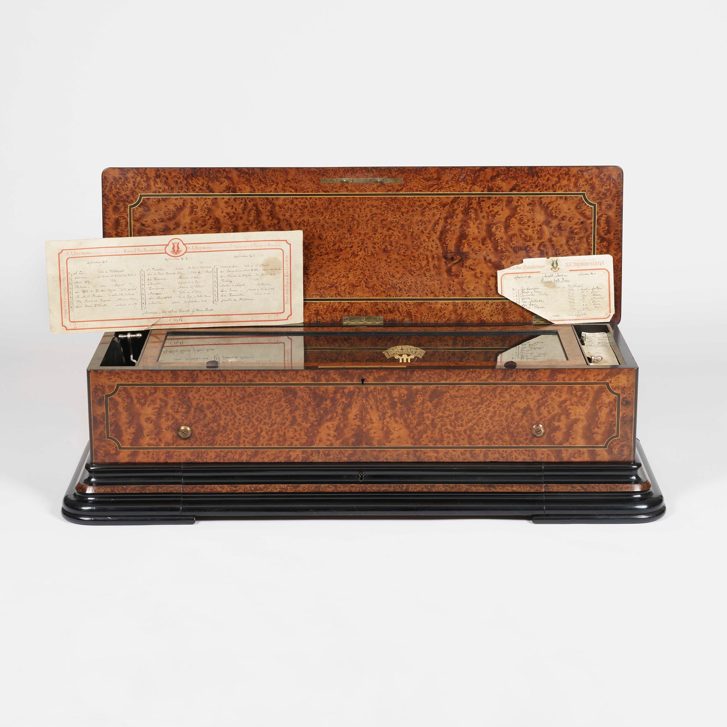 A splendid music box, numbered 20482
By B.A. Bremond of Geneva

The rectangular box, with a hinged lid, a drawer for the spare cylinders to the front, is constructed in amboyna, with boxwood stringing, and ebonised accents; there are four