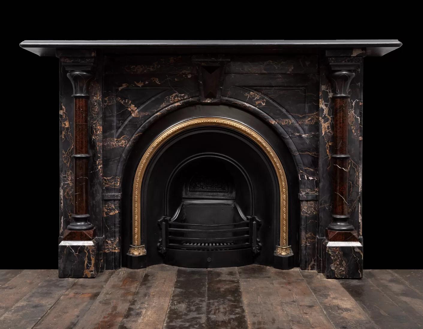 A grand antique Victorian marble fireplace made from Nero Portoro, Mazy Black and Serpentine marbles.
The richly coloured Portoro marble body is adorned with Serpentine pillars, Serpentine centre keystone and black marble lotus leaf capitals,