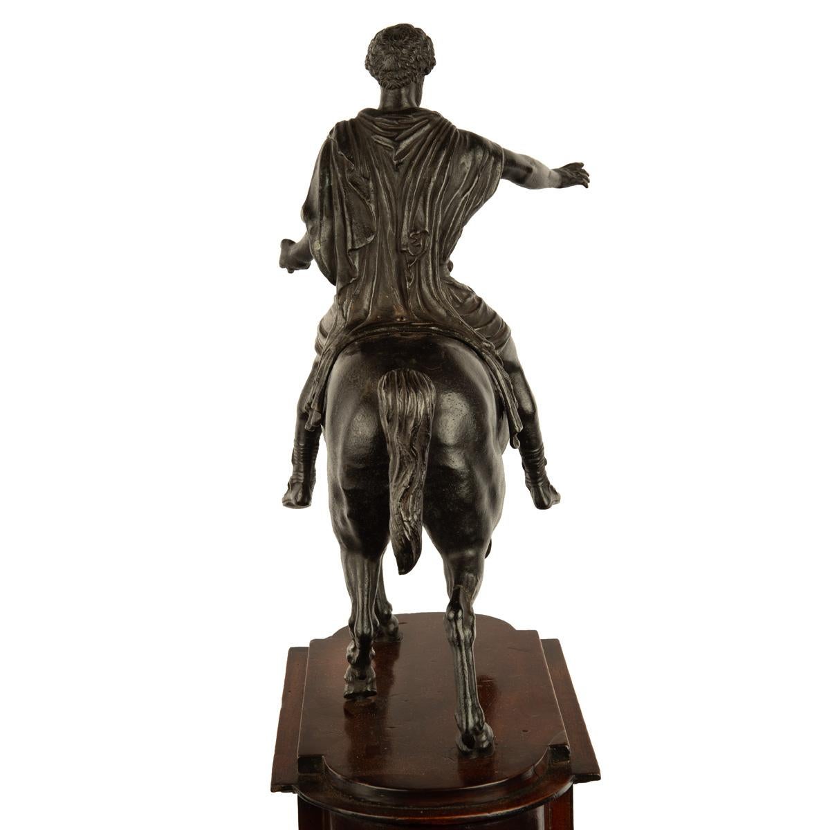 A Grand Tour equestrian bronze of Marcus Aurelius, after Hopfgarten, after the antique, shown astride a prancing horse with no reins and a Sarmatian saddlecloth with no stirrups, his right hand outstretched, raised on a shaped mahogany plinth inset