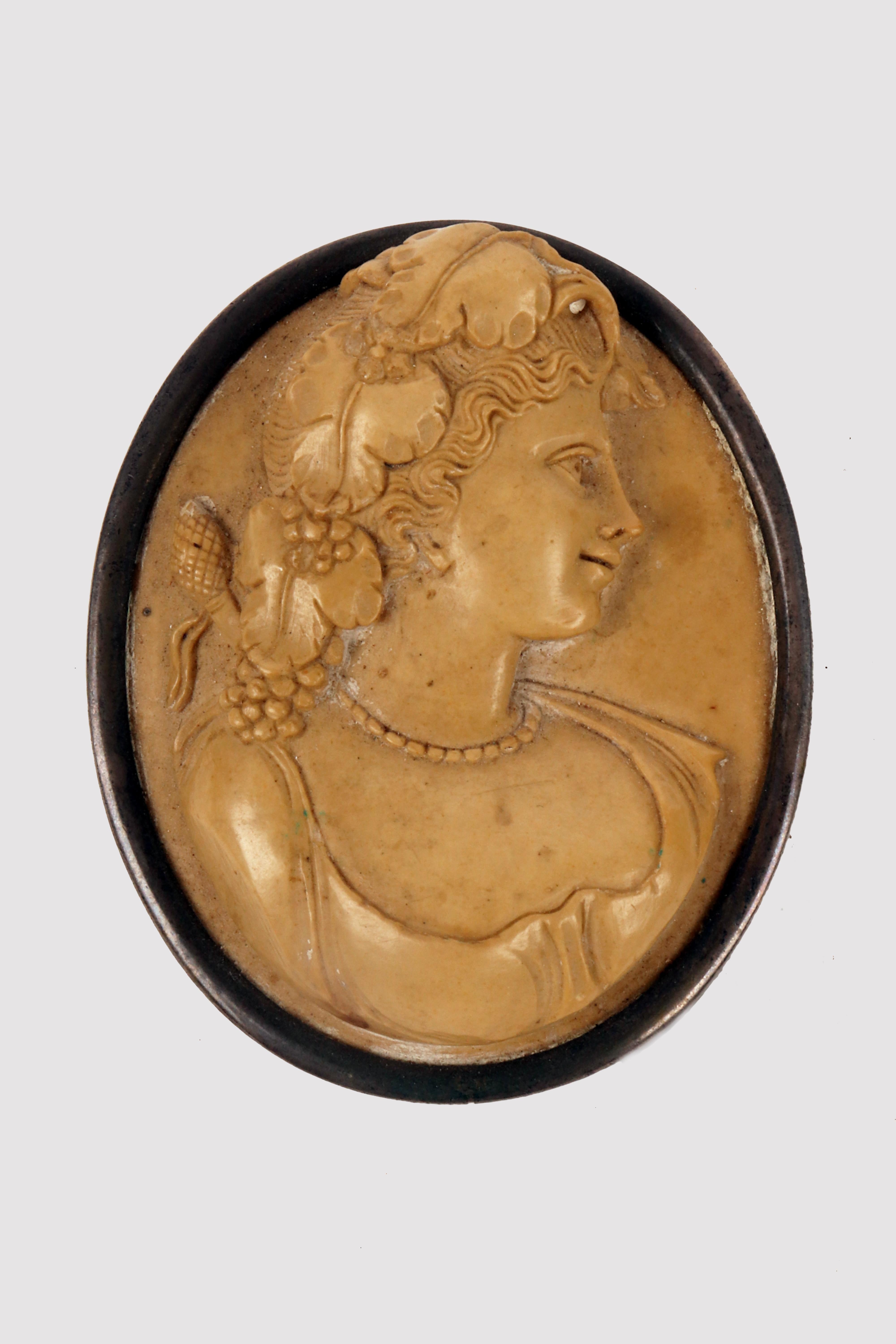 Big oval cameo made of lava and mounted in patinated silver with a smooth profile. On the front is sculpted a female bust with a rich hairstyle in which decorative elements belonging to the Dionysian world (a maenad?) can be seen such as the pine
