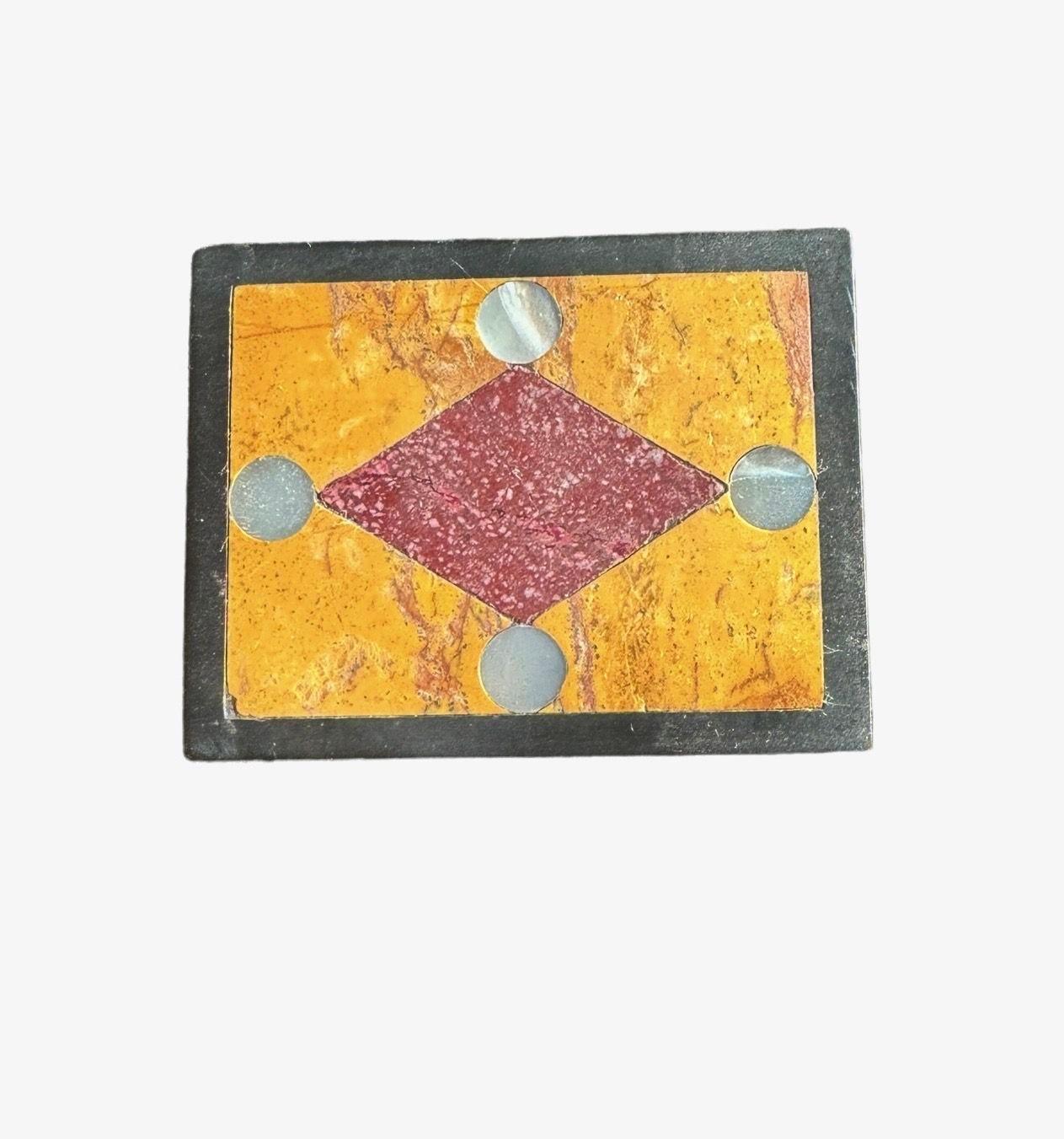 A rectangular shaped paperweight with inset Porphyry, Siena Marble and Mother of Pearl in black marble framework