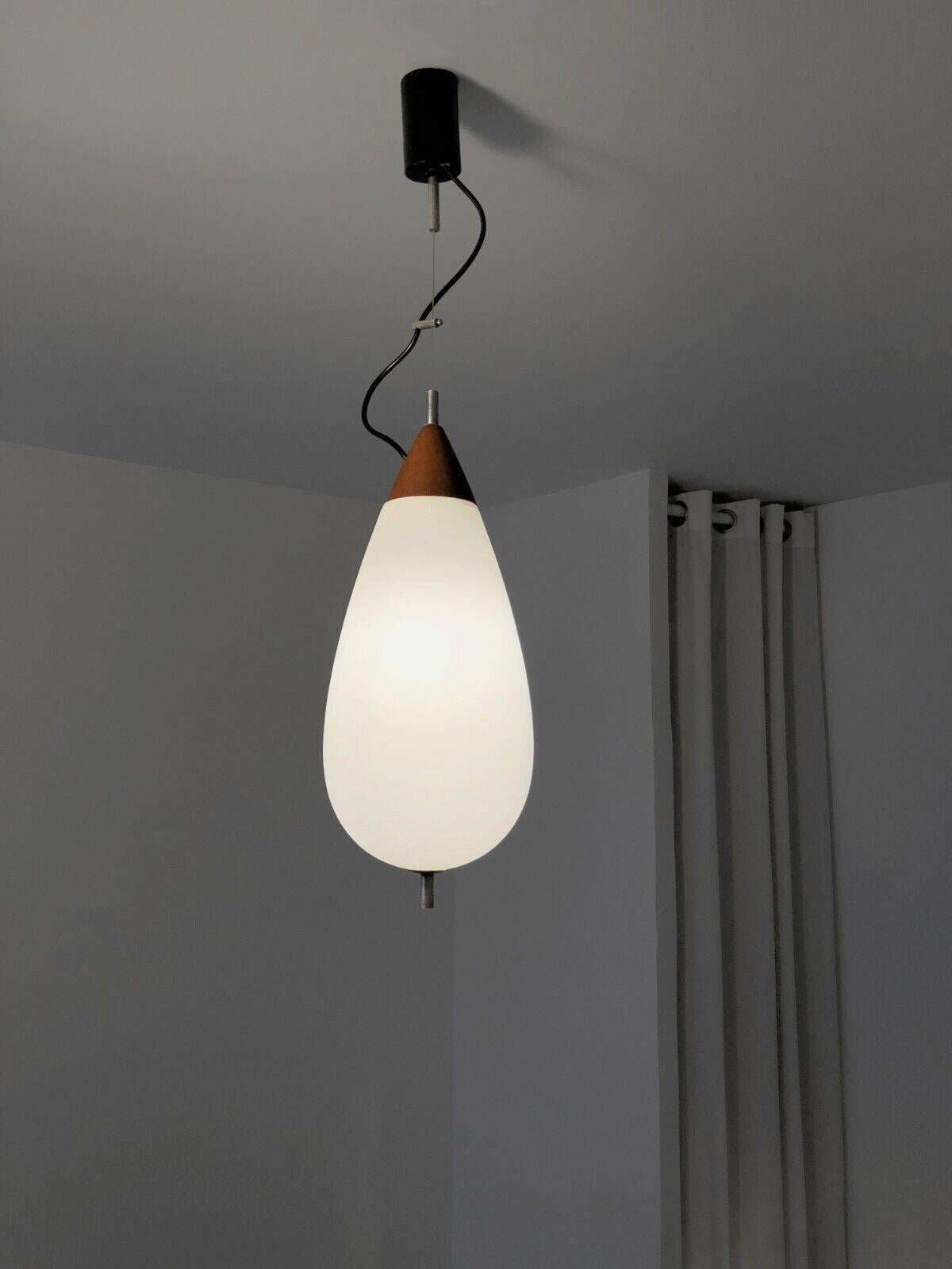 A sensual, graphic and airy pendant light, Modernist, Free-Form, Space-Age, with an ovoid drop body  diffusing white light, opaline glass mounted on a red-brown wooden base, modular structure with iron wire and black electric wire creating a
