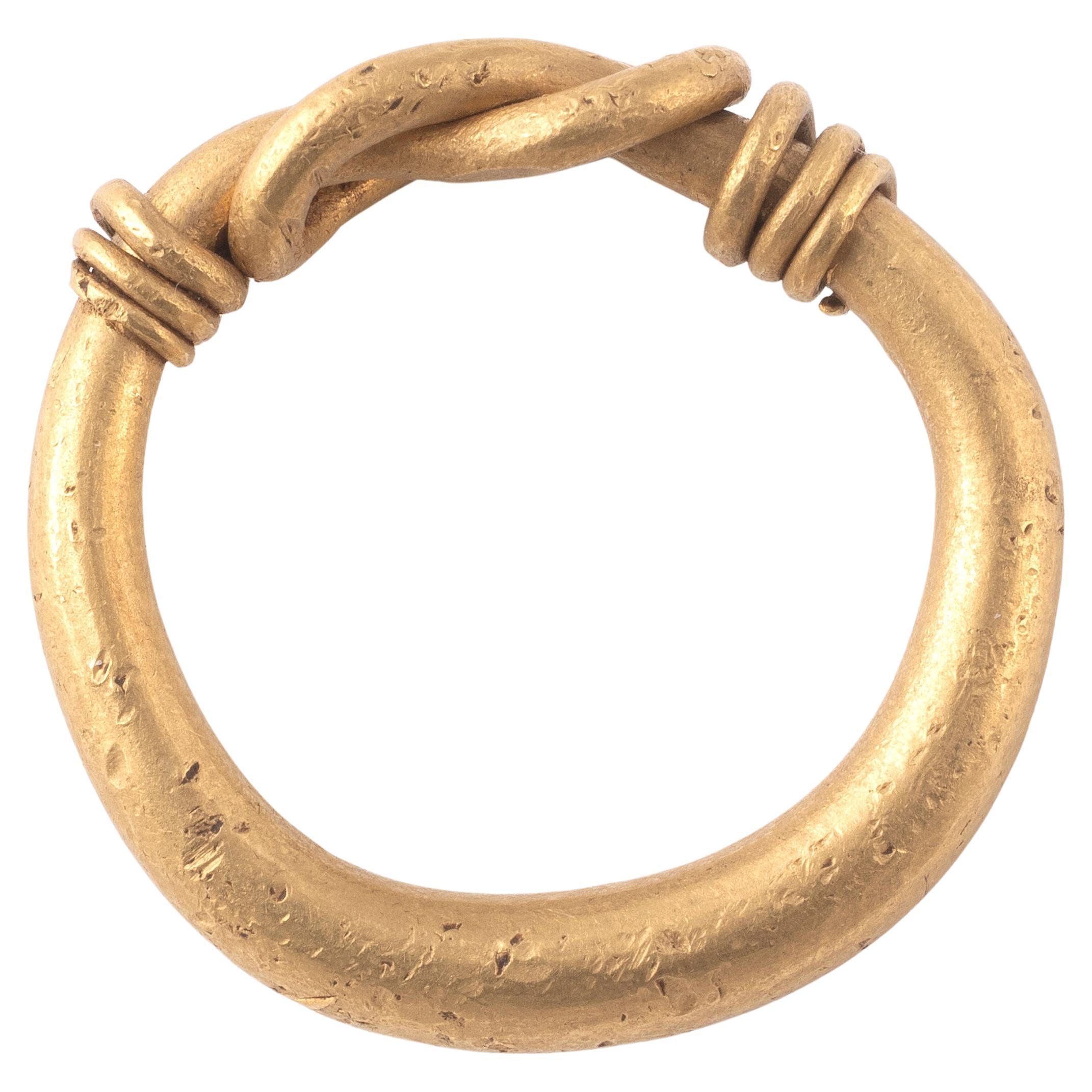 A greek high karat gold ring. Hercules' knot. The ring is characterized by a flat hoop, ending with two connections (thicker, and worked with a dotted thread), from which an elegant Hercules's knot originates. Hellenistic work, Magna Graecia.