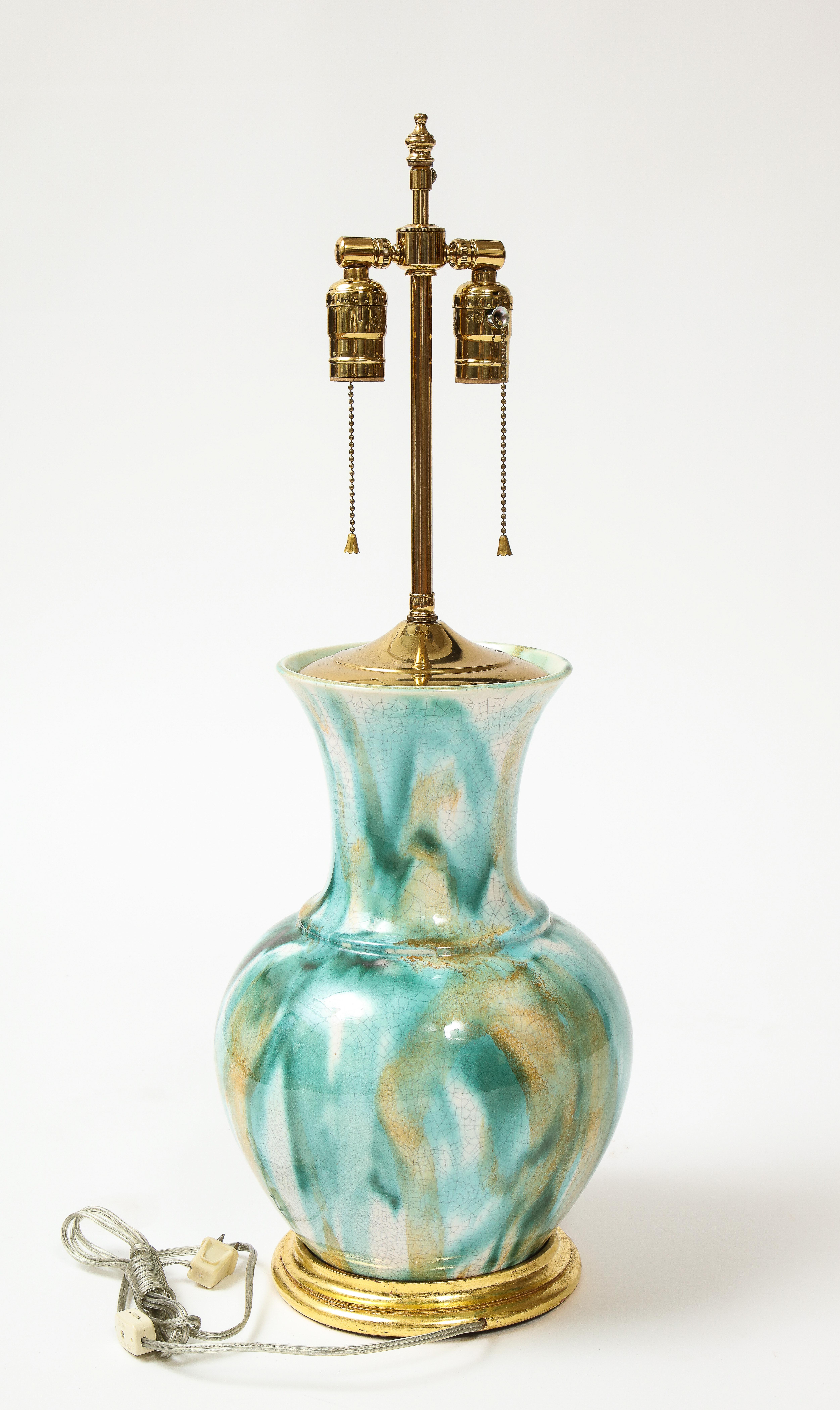 Of baluster form and marbled overall in green and orange glaze on a white ground, mounted on a giltwood turned base; fitted with brass bulb sockets and adjustable rod for height. American.