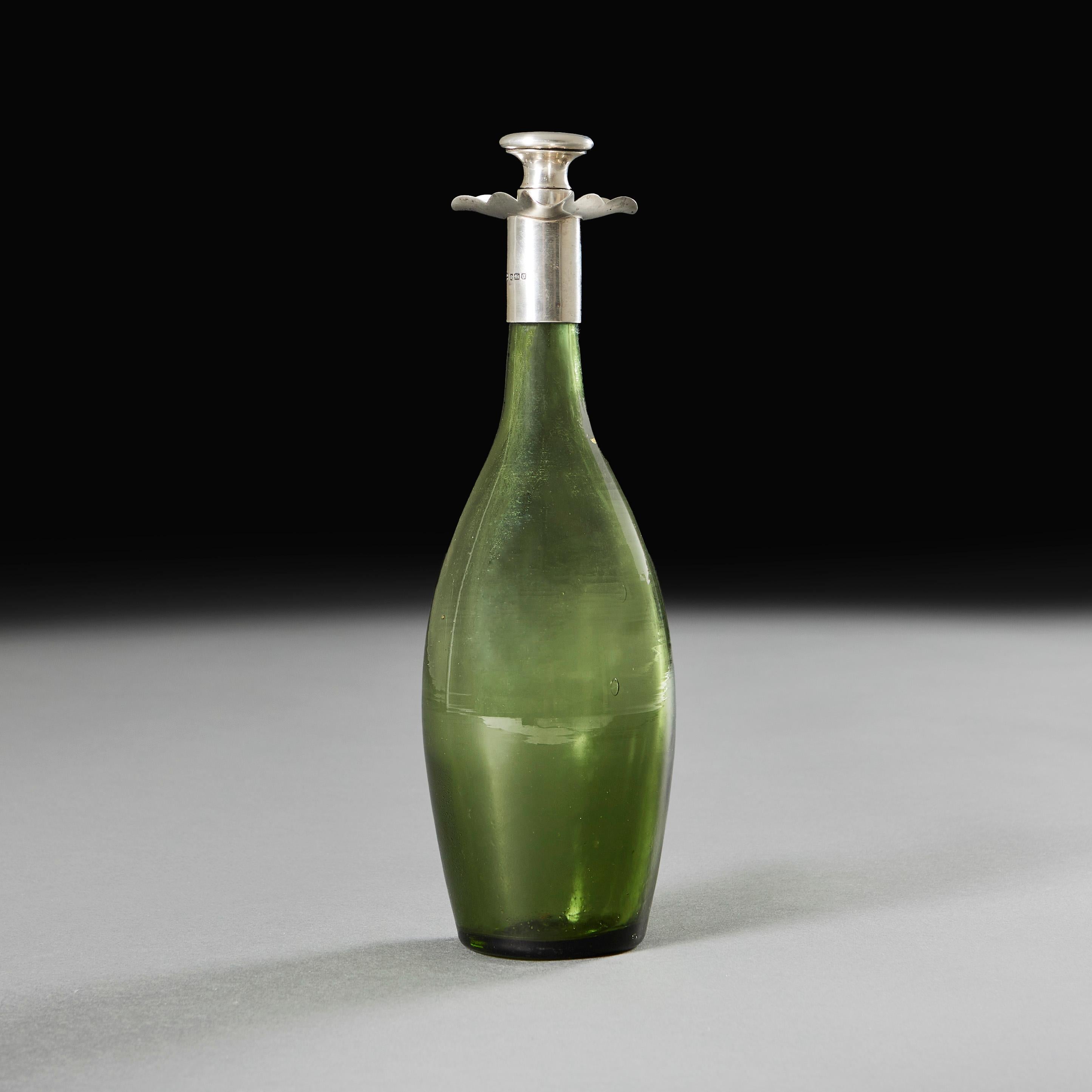 An Edwardian light green glass spirit decanter with silver collar and unusual trefoil pouring system, with circular silver stopper engraved with an M. Hallmarks to the collar and stopper. By James Deakin & Son, Sheffield, Founded 1866.

Sheffield,