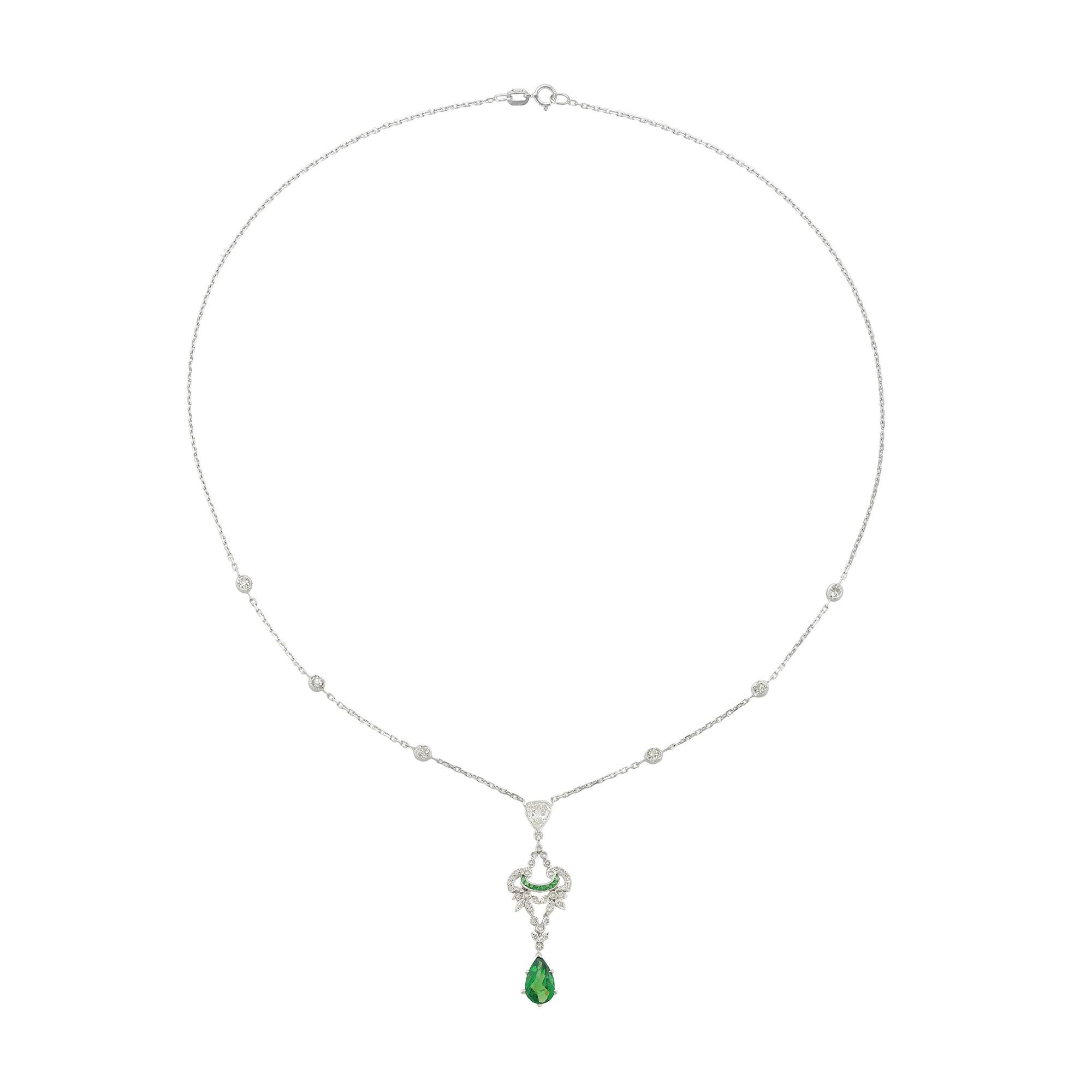 A green tourmaline and diamond drop pendant, the openwork scroll and foliate design plaque millegrain-set with small Swiss-cut diamonds and eight calibre-cut green garnets, with a pear-shaped rose-cut green tourmaline drop, all suspended by an old