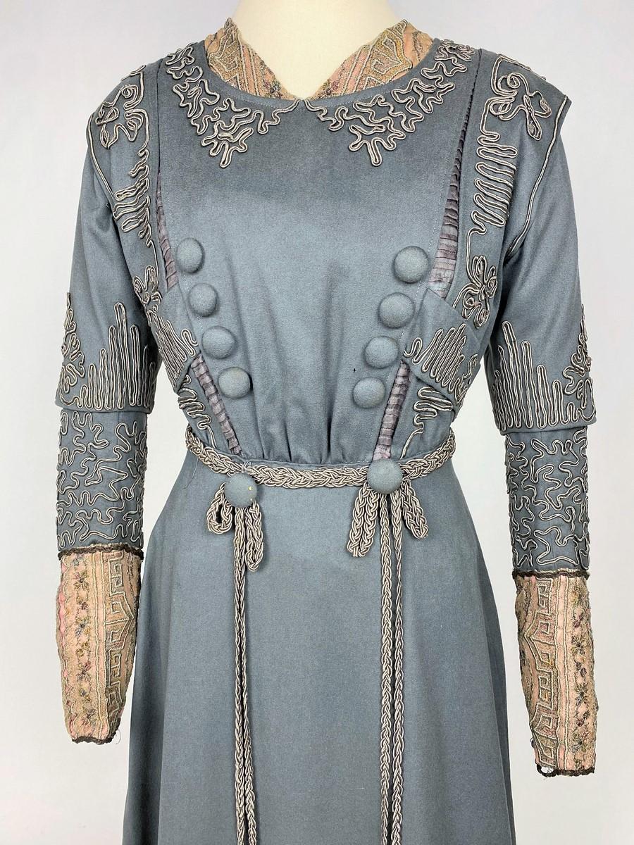 Circa 1905-1910
France or Europe

Beautiful young girl's afternoon dress in mouse-grey wool felt applied with cordonnets in a vermiculated design in colour and dating from the Belle Epoque. The dress is straight, with a high waist and yokes on the