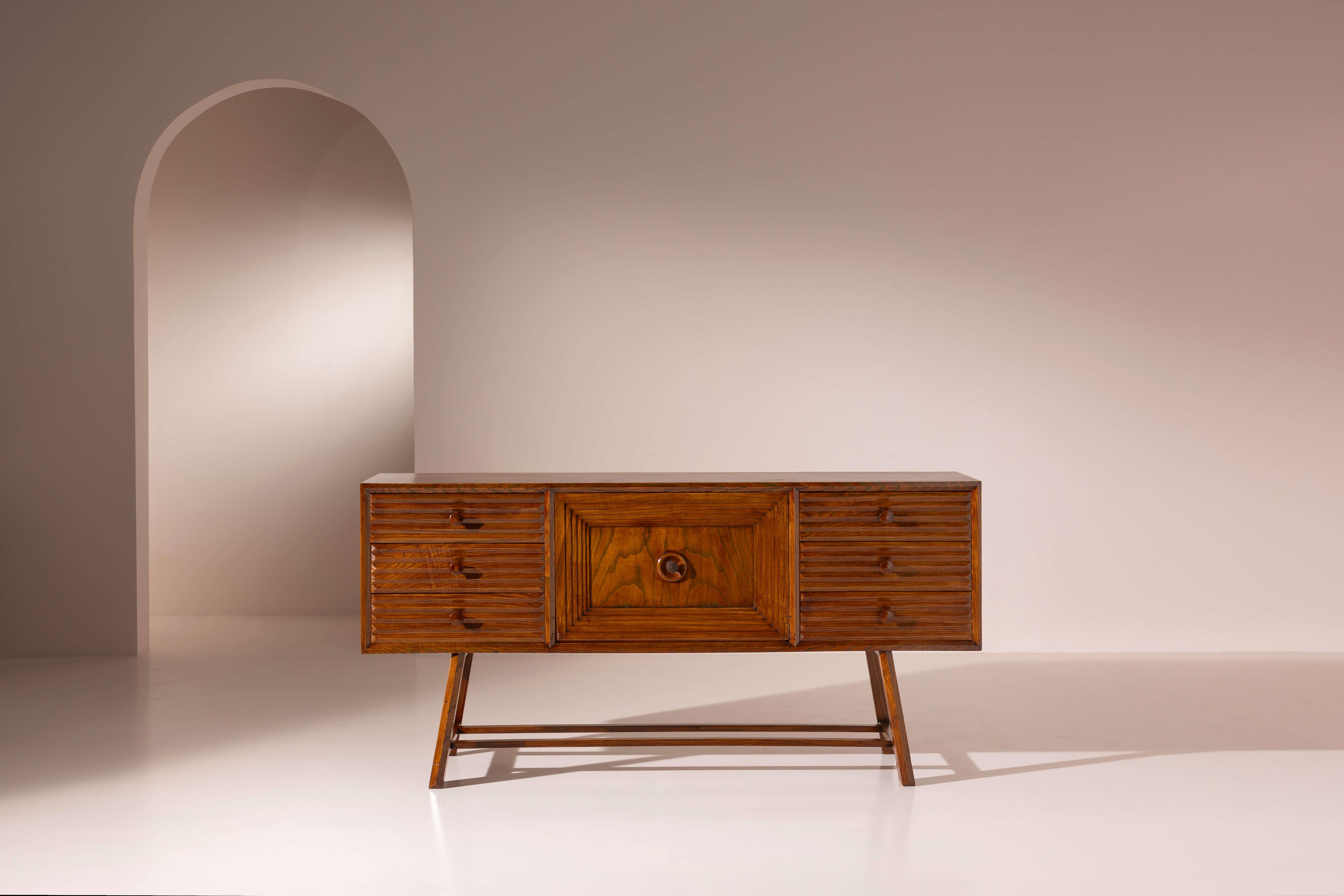 Aparador italiano de mediados de siglo en madera de castaño con cajones y puerta abatible, frentes de cajones decorados, Italia, años 50

Este aparador italiano de mediados del siglo XX parece el testimonio de un momento histórico preciso.