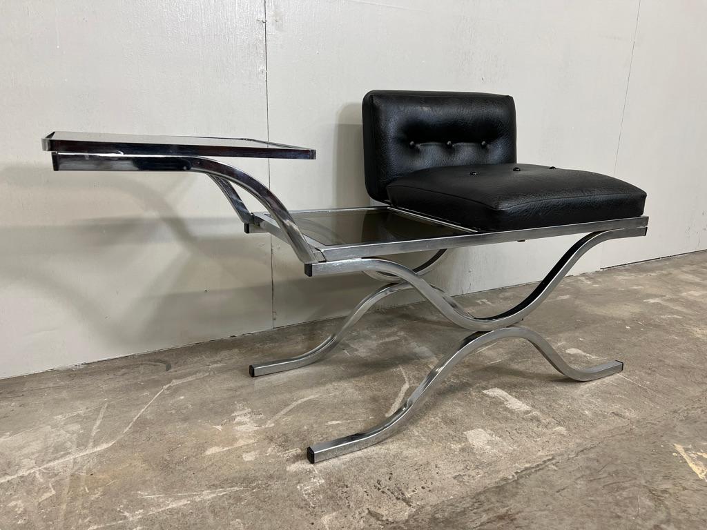 Remember when making a phone call required a piece of furniture? A groovy, late 60s/early 70s telephone table, the seat is upholstered in a classic black buttoned atomic design on a chrome metal base, it has two glazed table tops. The table frame is