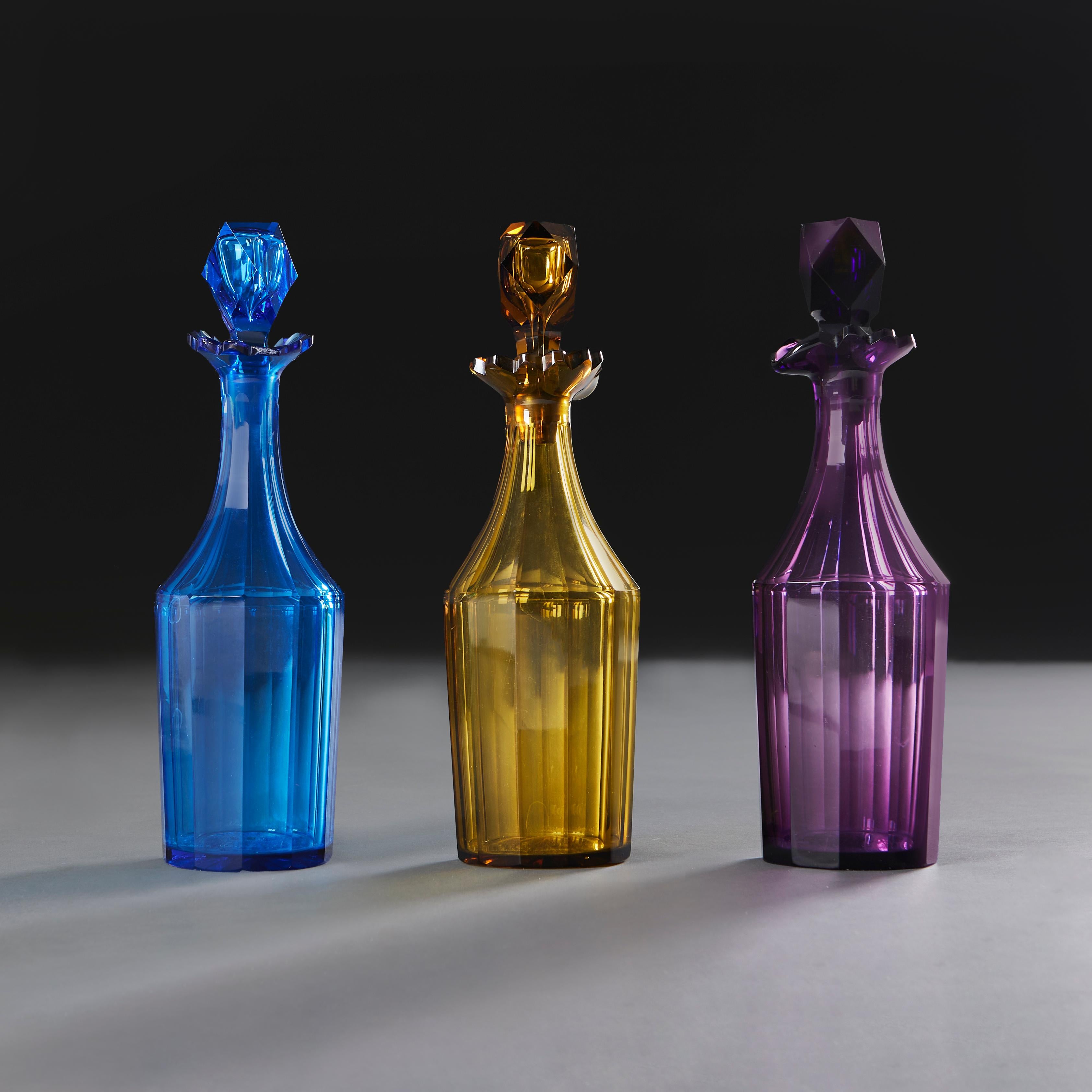 Un gruppo di tre decanter per liquori del XIX secolo di colori diversi, con lati sfaccettati, bordi ondulati e tappi sfaccettati. Un decanter con abrasione sul bordo.

Altezza    29.00cm

Diametro  9.00cm