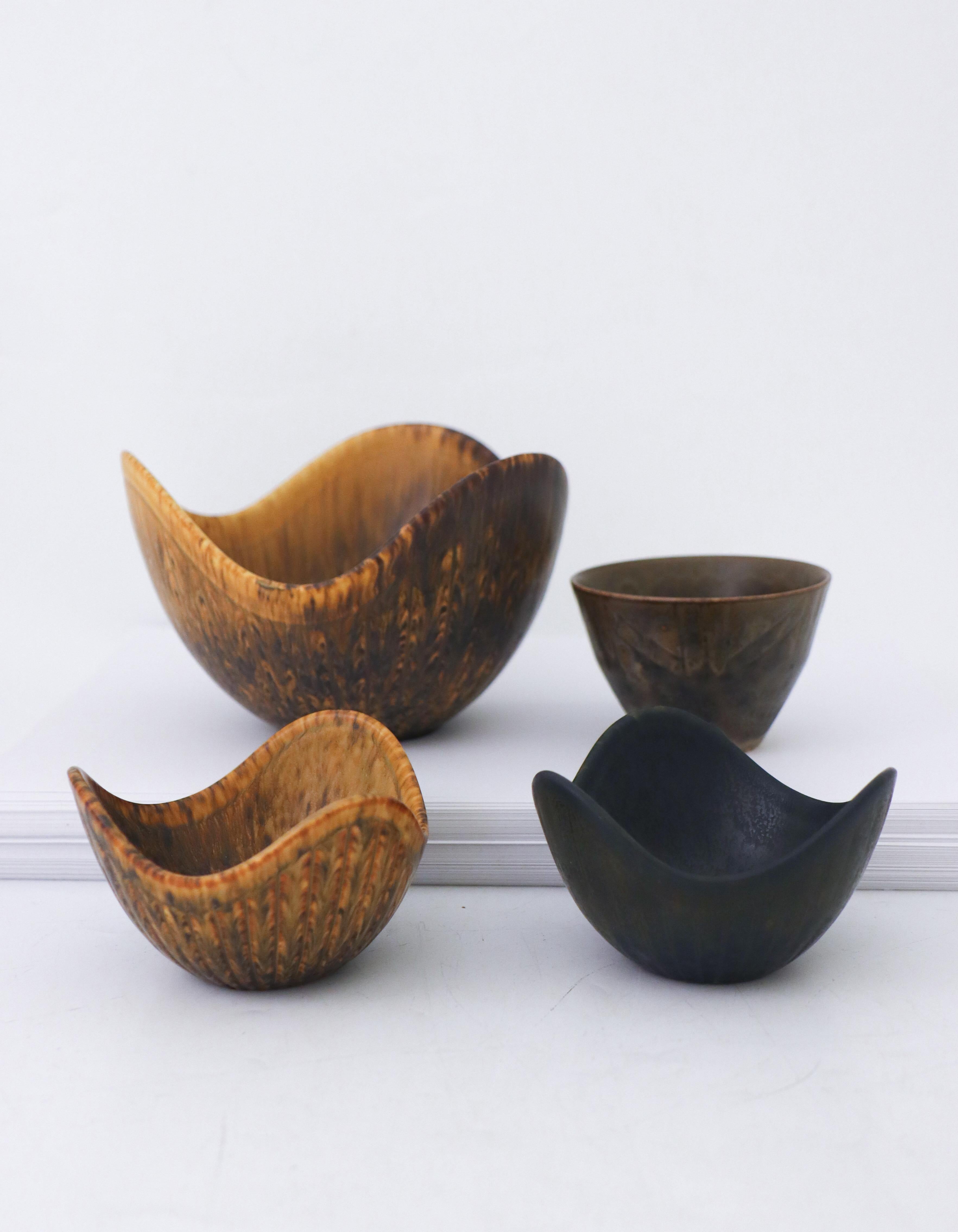 A group of four bowls designed by Gunnar Nylund and Carl-Harry Stålhane at Rörstrand. The three bowls in the same shape are designed by Gunnar Nylund, the larger one is 13.5 cm in diameter and the two smaller once are 8.5 cm. The gray bowl to the