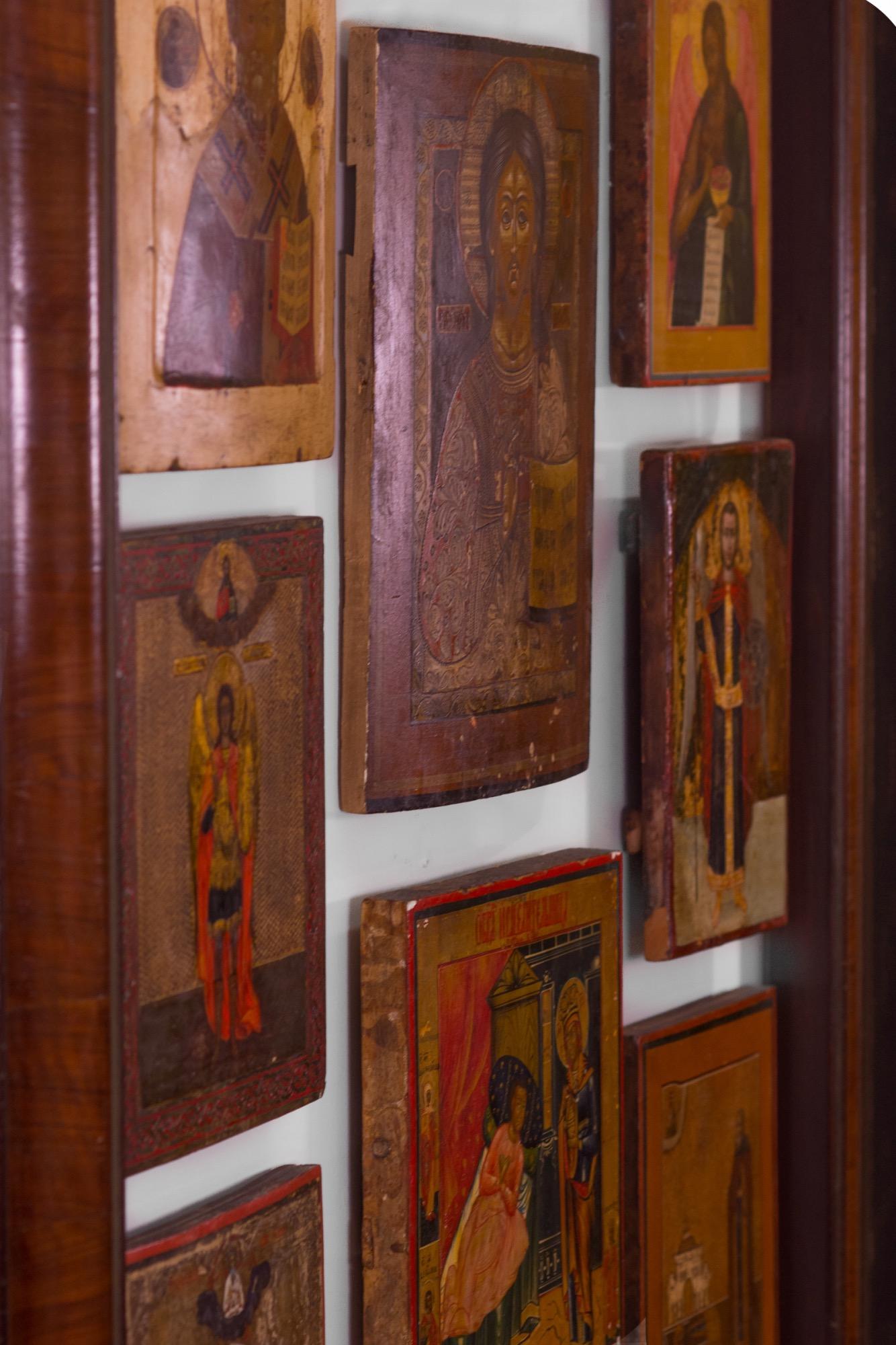 Un groupe de huit icônes orthodoxes russes et grecques peintes à la feuille d'or et au gesso, posées sur une planche de bois. Elles sont montées sur un panneau en Lucite et encadrées d'une moulure en noyer finie à la main. En haut à gauche : Icône