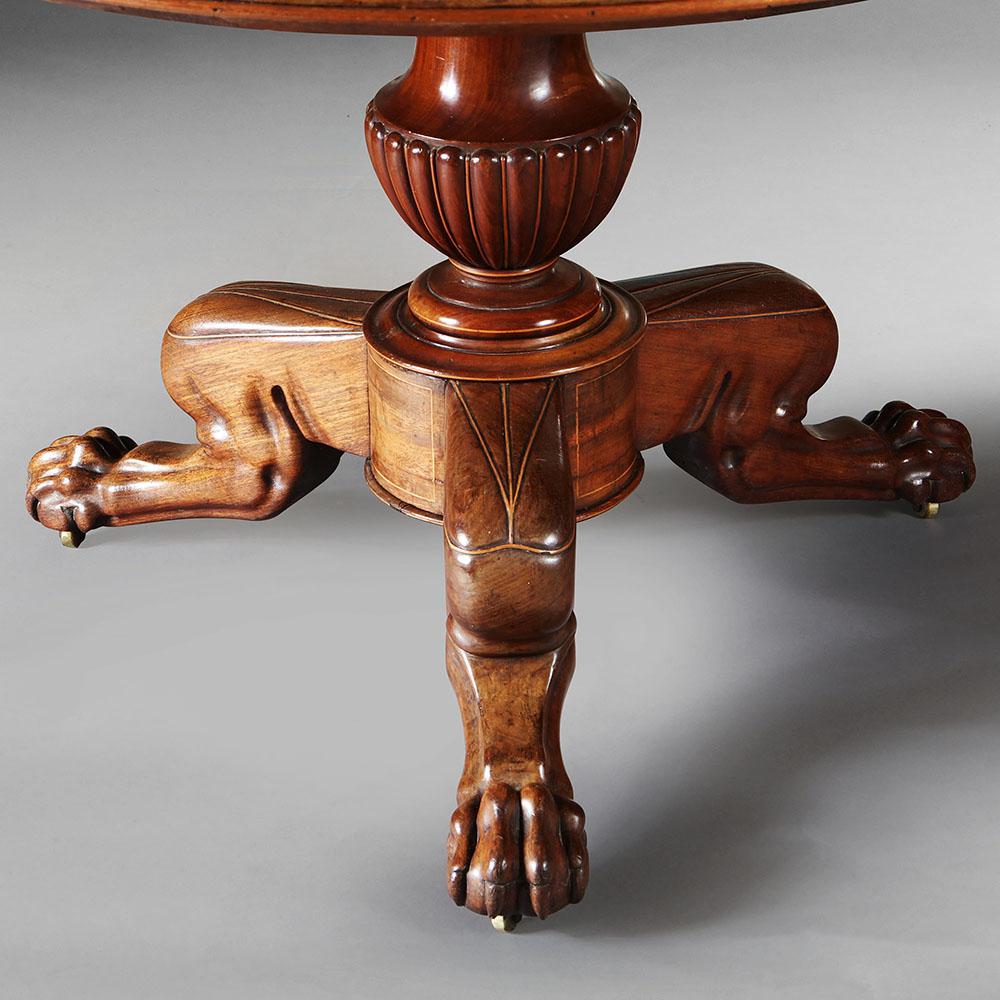 An early 19th century mahogany gueridon table with an inset grey marble top of bleu turcan, four drawers set into the frieze, the urn-shaped central column with three muscular leonine feet and inlay.
