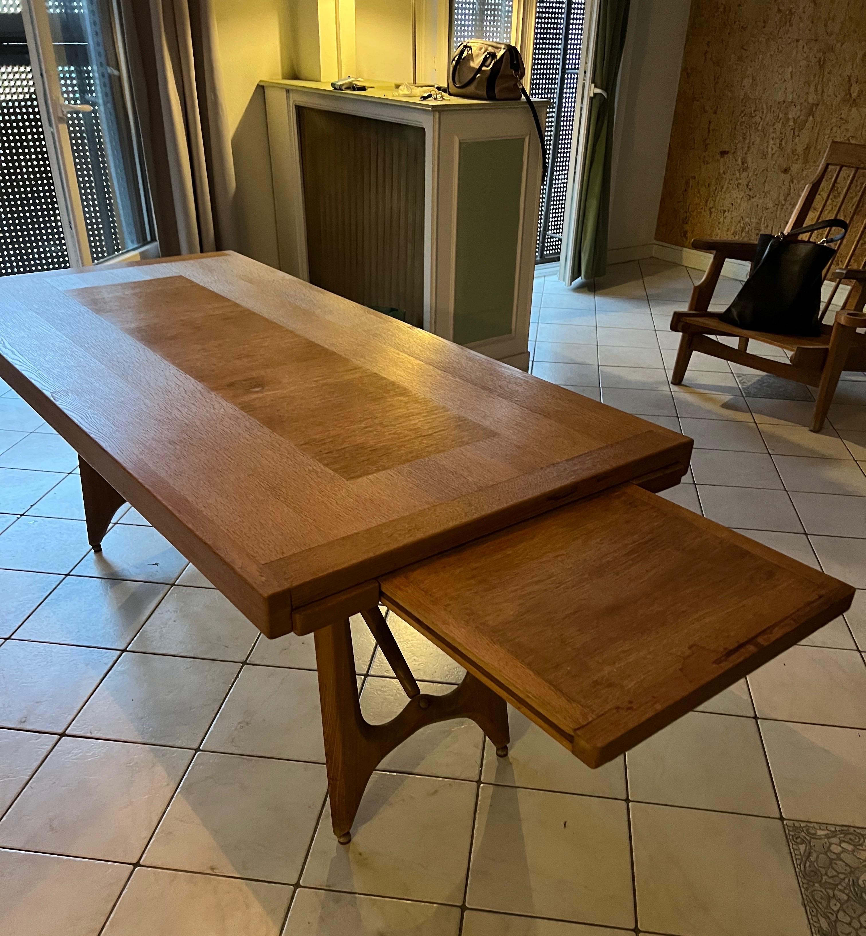 An oak dining table with two leaves incorporated of approximately45 cm each by Guillerme et Chambron edition votre maison.