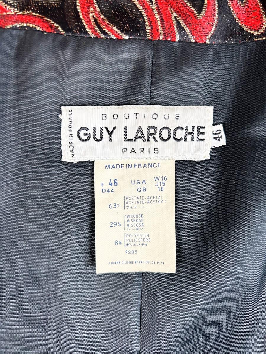 Circa 1985
France
Shoulder-length jacket in lamé polyester by Guy Laroche dating from the Disco years around 1985. Radiant lamé on a black background with a swirl pattern of red and gold streamers. Fitted jacket with a small turned-up officer's