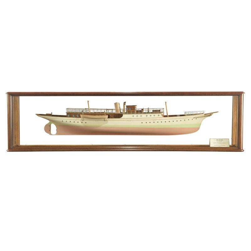 This fine shipyard half-hull model has a painted pink hull with a pale green waterline and white topsides with a line of portholes.  There are two truncated masts, a funnel and a bowsprit above an eagle figurehead. The decks have a coach house and