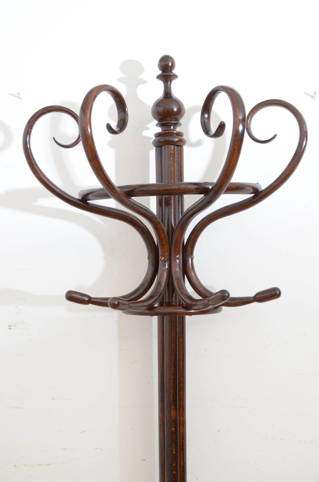 St031 A half round bentwood hat stand, having four coat hooks and four bentwood scrolls for hats, surmounted by a turned finial, supported on cluster column terminating in three downswept legs with a ring for sticks and umbrellas. Ready to place at