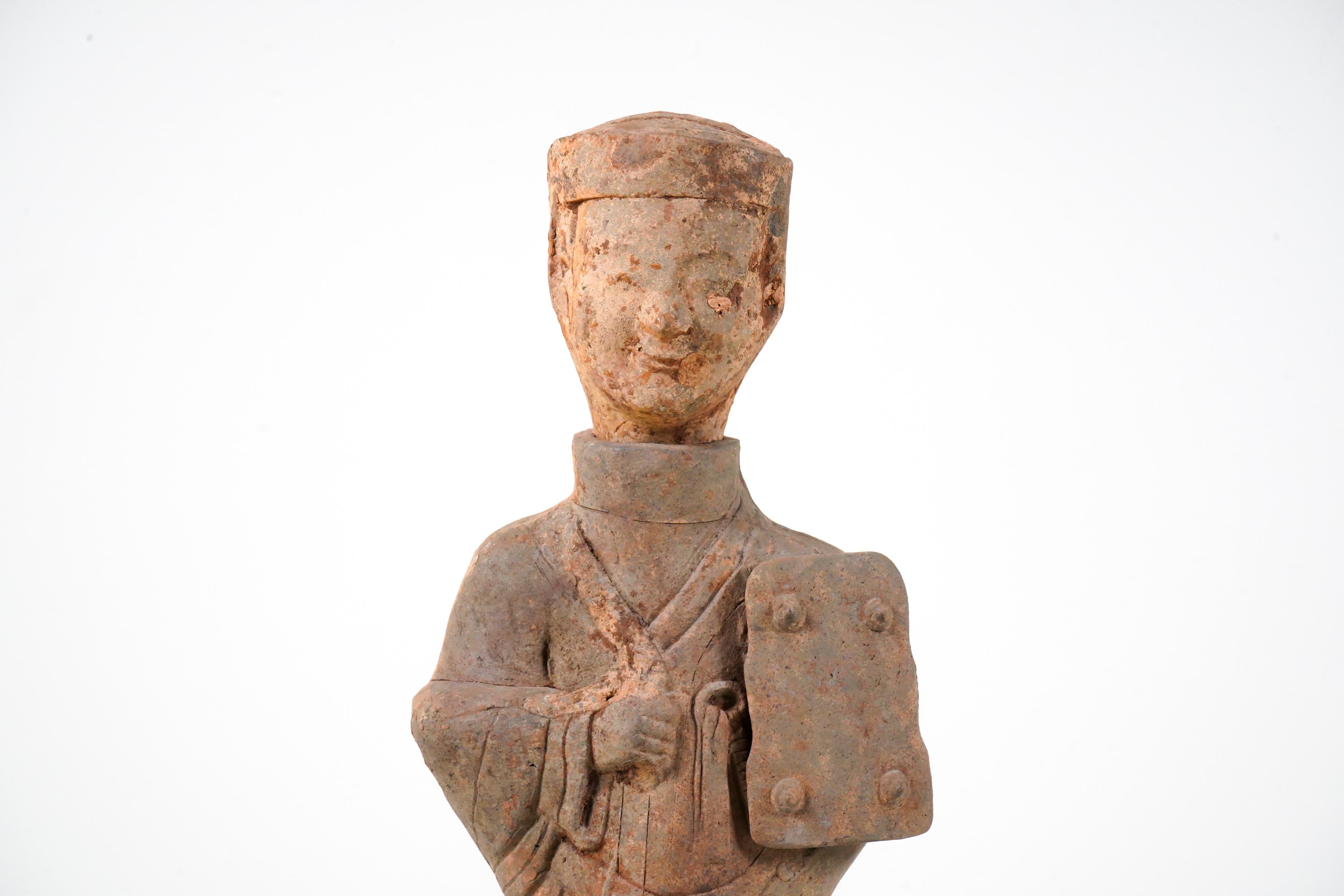 A large Chinese terracotta tomb figure (Ni Yong) from the Eastern Han Dynasty (25-220 AD), likely from the area of modern-day Sichuan. It appears to depict a groom in full costume and harness in hand. With a flat top hat and knotted robe, the figure