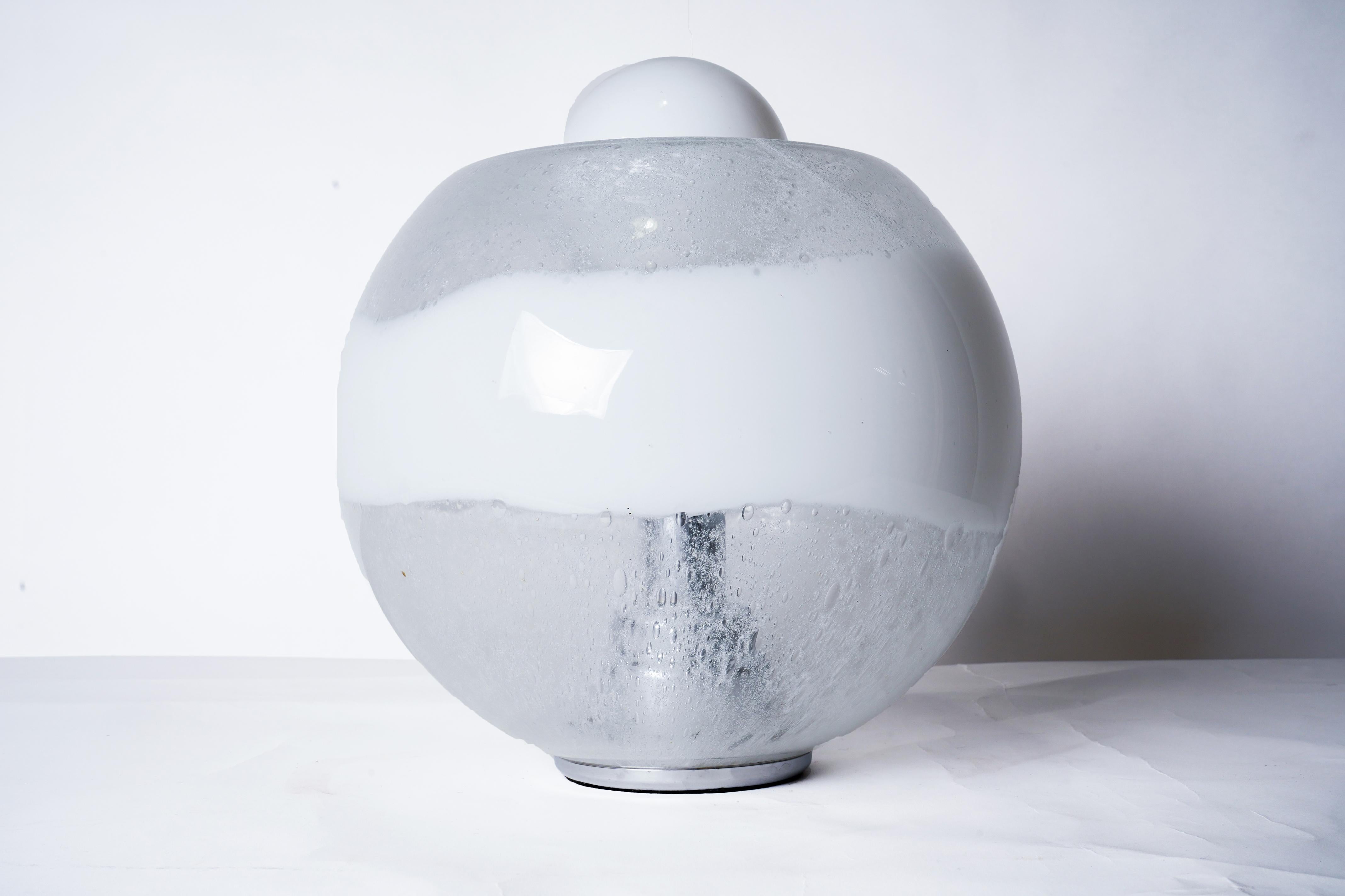 A Murano glass lamp with metal base. For Mazzega, Italy.  The large heavy globe is made from white and clear glass and has an opening in the center, top and bottom.  The shade sits on a metal base which connects to an internal chrome shaft that