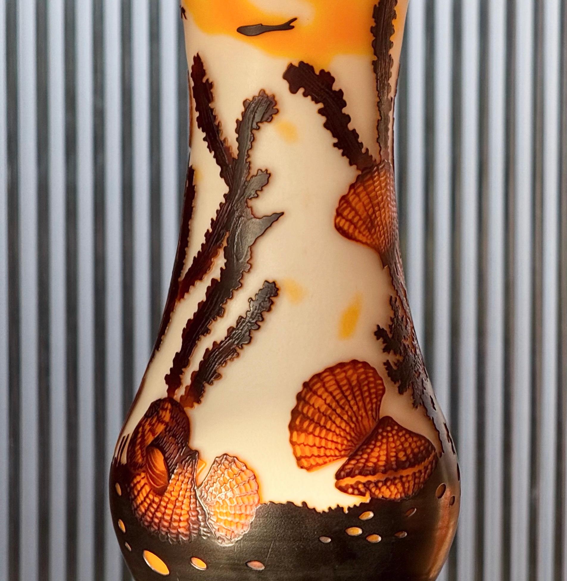 A hand-blown art glass vase after celebrated Art Nouveau artist Émile Gallé, 20th century. Featuring an embossed whimsical underwater motif of fish, conch shells, mollusks, and undulating kelp; in tones of saffron, sienna, espresso, and ivory. Even