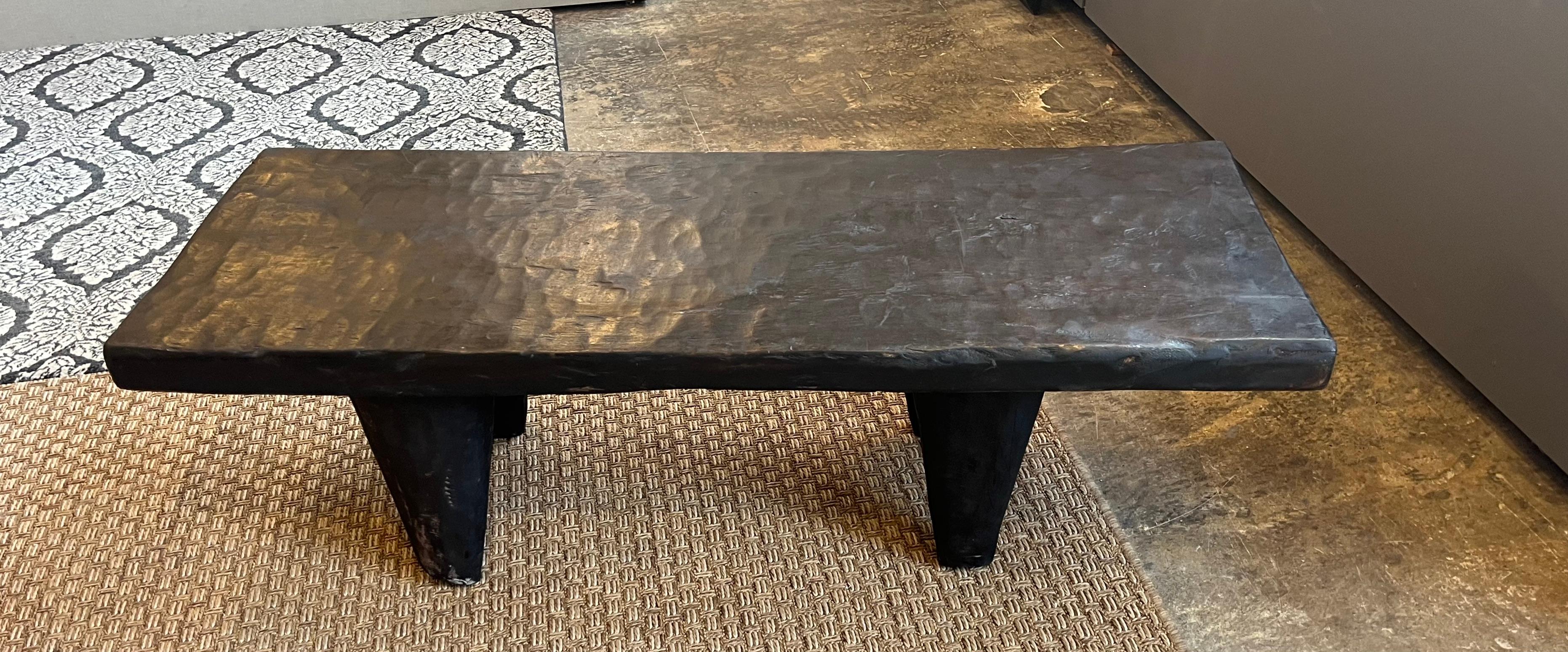 A hand carved Iroko wood low table or bench from the Ivory Coast of Africa. This table was carved from a single piece of wood.The presentation results in a rustic but elegant table.