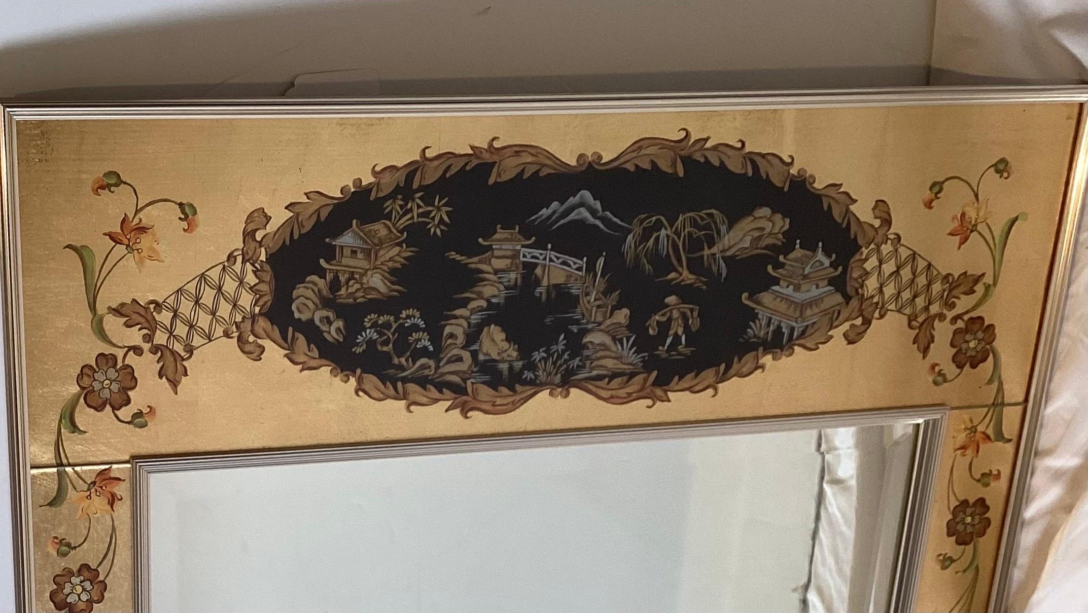 Elegant miroir mural biseauté encadré en églomisé et peint à la main.  Le cadre signé par l'artiste et daté de 1978 présente un décor inspiré de la chinoiserie.  Le miroir biseauté est encastré, avec un bord extérieur en laiton et un support en bois