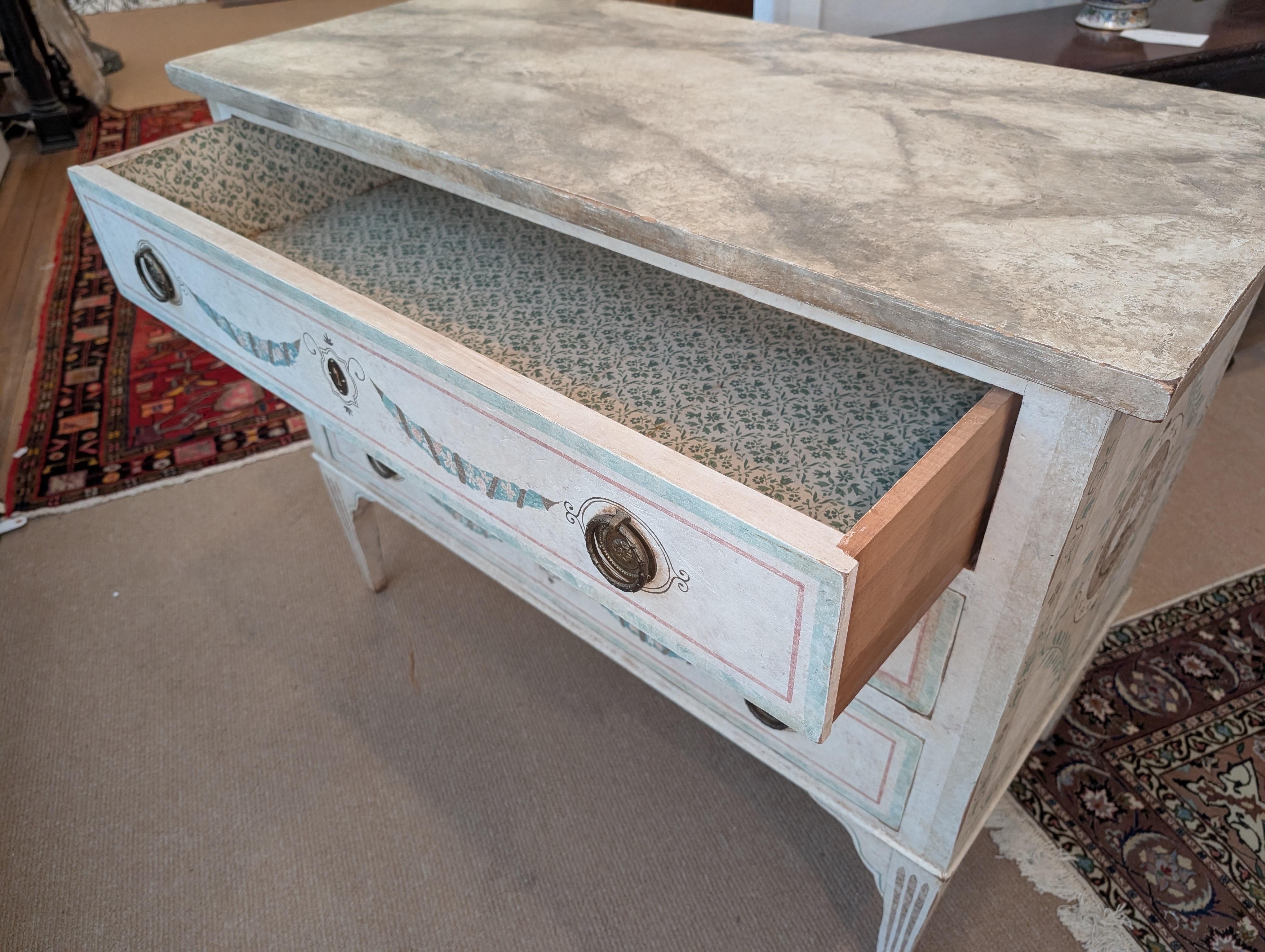 Un elegante comò Nierman Weeks dipinto a mano.  Il piano è in finto marmo dipinto con un corpo strutturato in crema con decorazioni di cigni e ghirlande. 