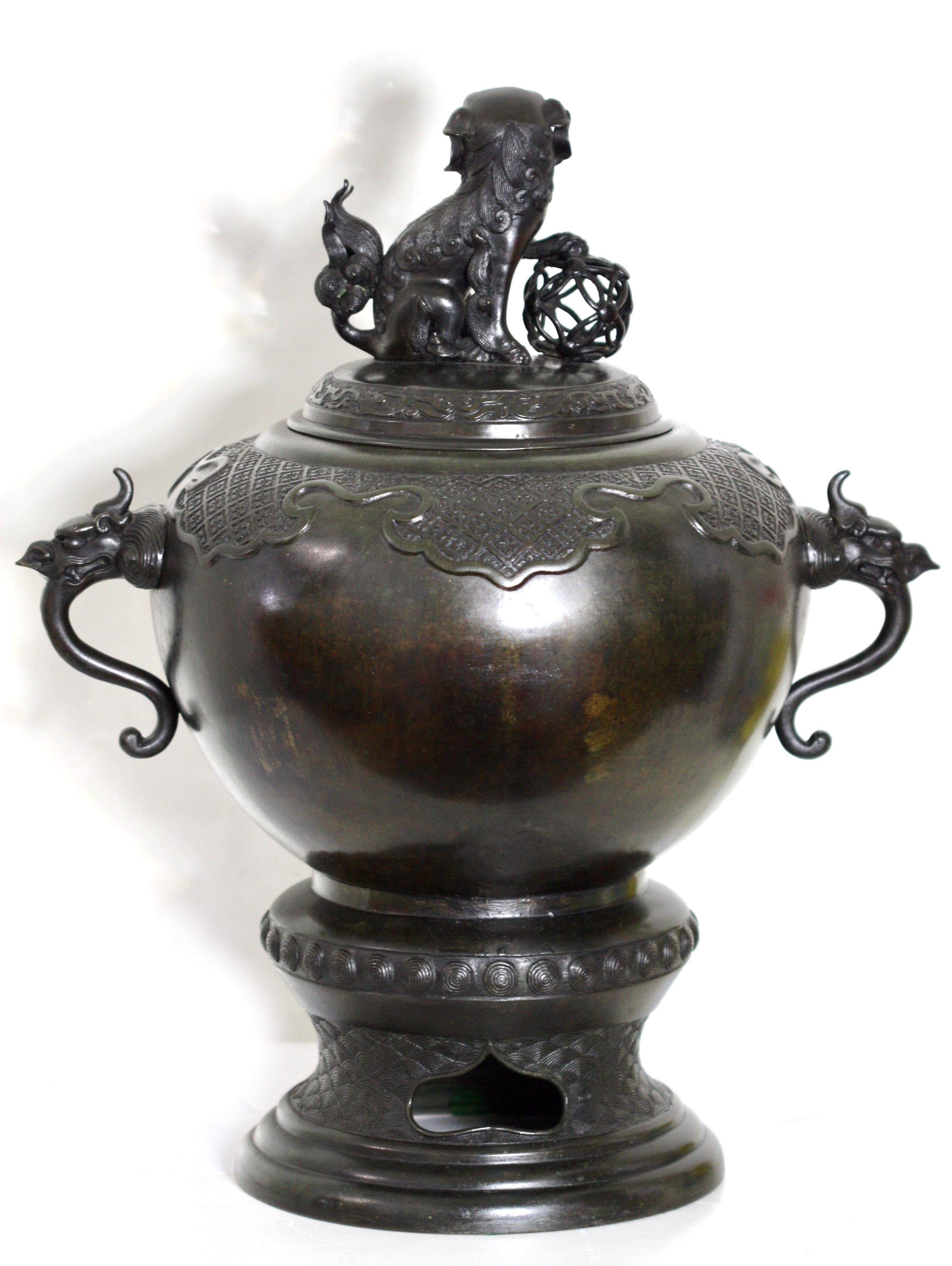 
Un beau centre de table en bronze japonais ancien pour une table d'autel, sous la forme d'une urne sphérique couverte avec des poignées en forme de tête de dragon, une base de piédestal surélevée et un pommeau expressif en forme de lion du temple