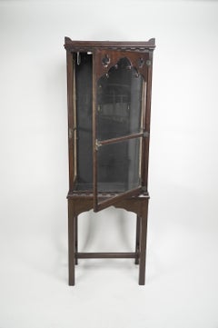 Gothic Revival oak display cabinet with arch & quatrefoil decoration on a stand.