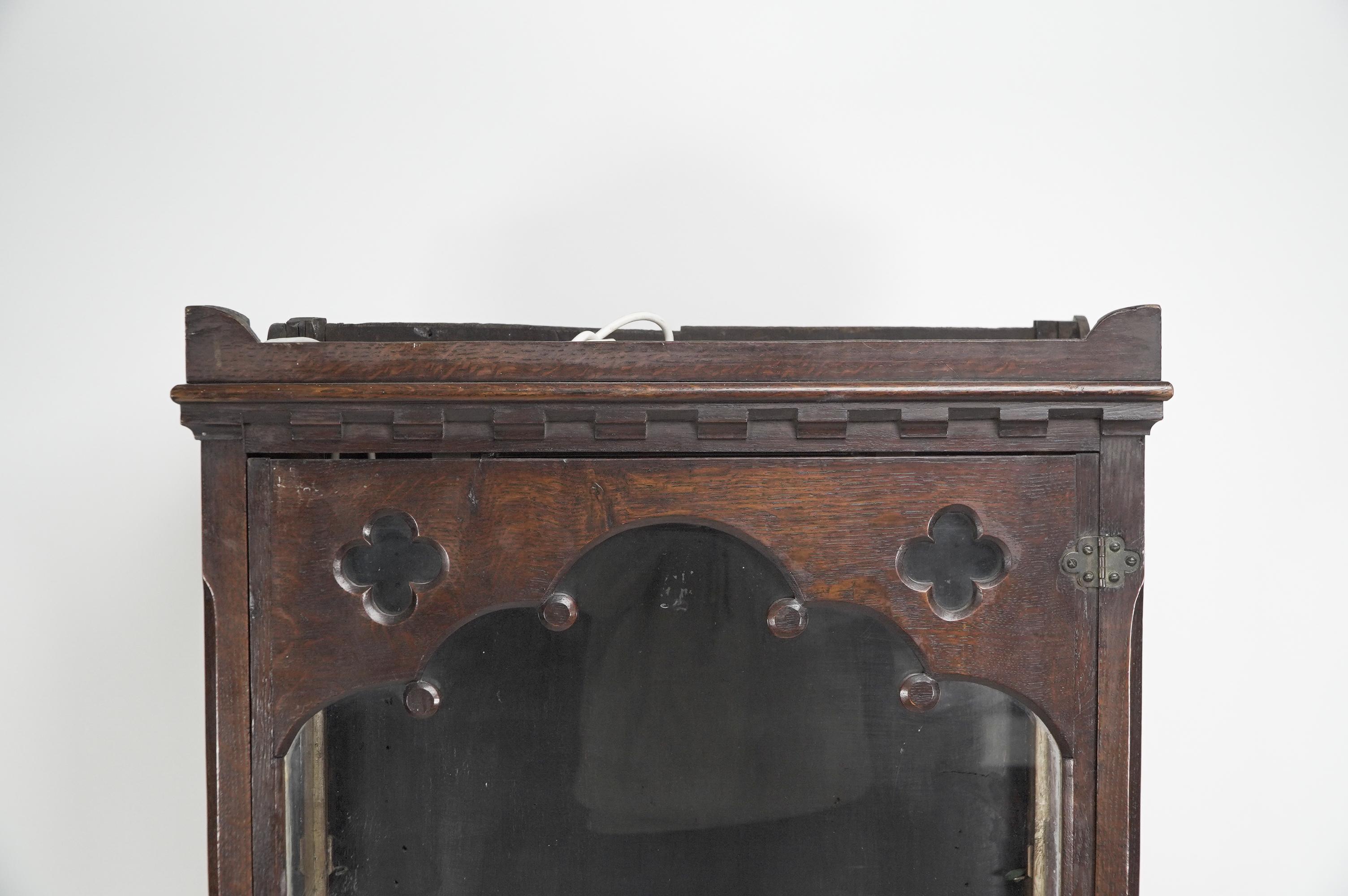English Gothic Revival oak display cabinet with arch & quatrefoil decoration on a stand. For Sale