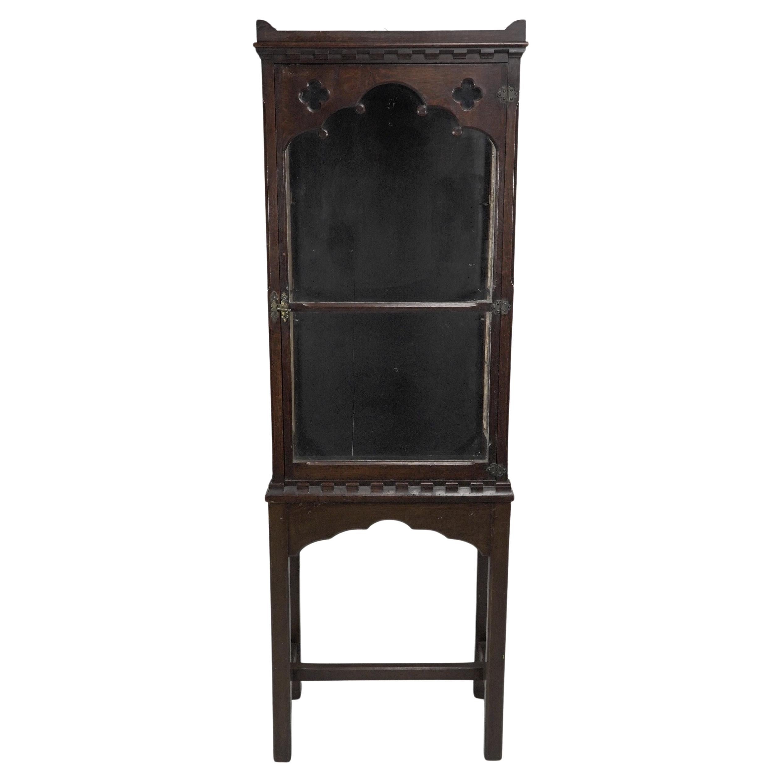 Gothic Revival oak display cabinet with arch & quatrefoil decoration on a stand.
