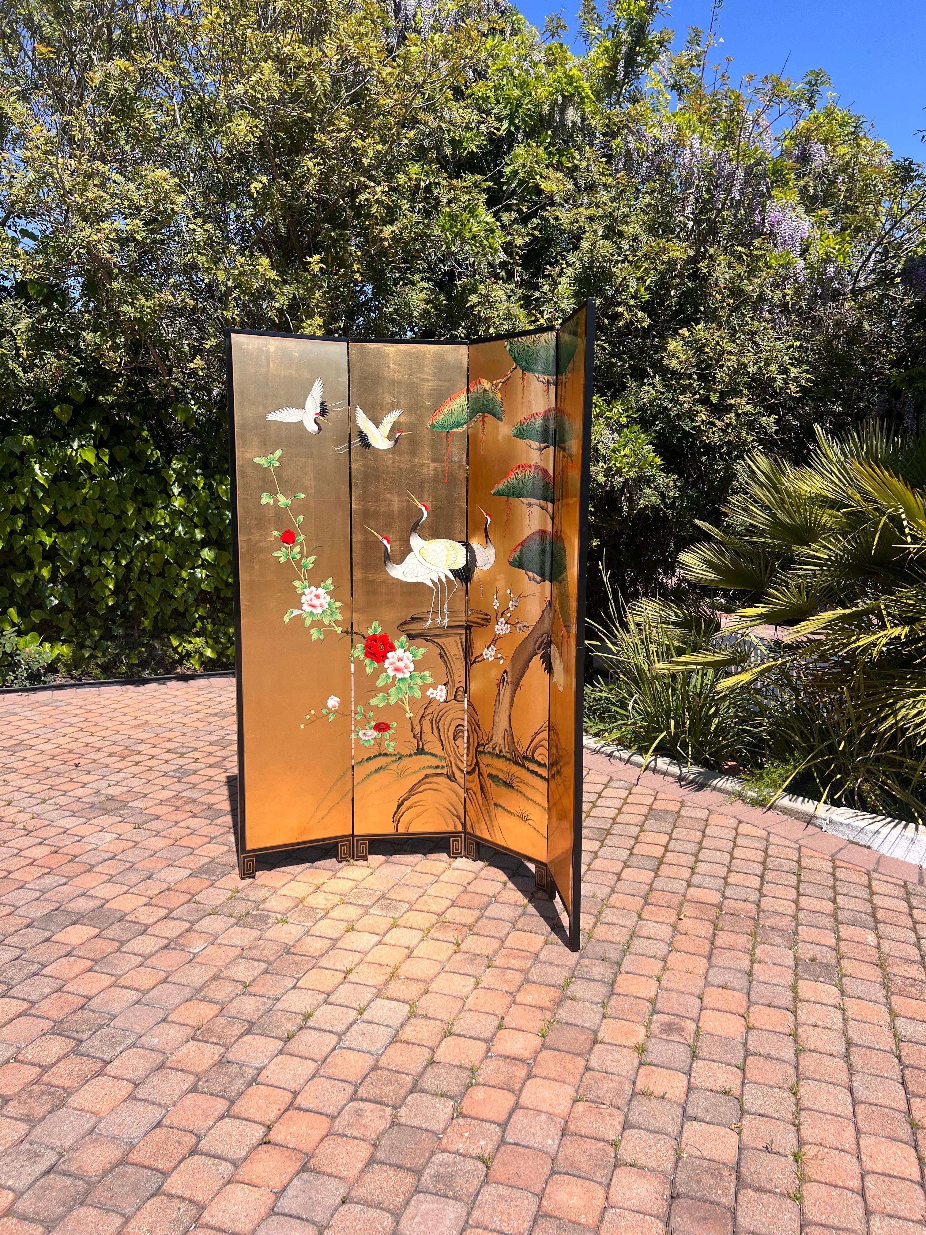 A handsome vintage oriental partition or room divider, 20th century. Hand-painted with Asian birds and flowers in tones of licorice, maraschino, and frond green against a glowing golden backdrop. The verso of the partition is ebonized wood with