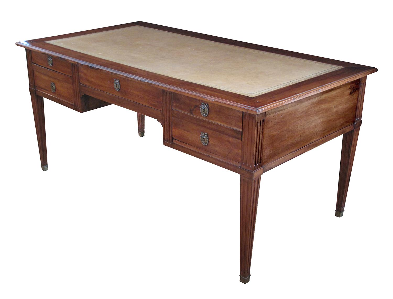 With hand-tooled pumice-colored leather top above 5-drawers all raised on tapering square-form fluted supports ending in brass caps; with finished paneled back.