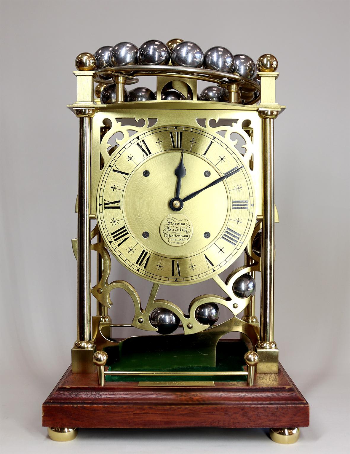 This is a novelty clock from the later half of the 20th century, powered by the weight of its twenty four steel ball bearings as they descend around the carousel wheel and are deposited in the green base trough in the base of the case. They can