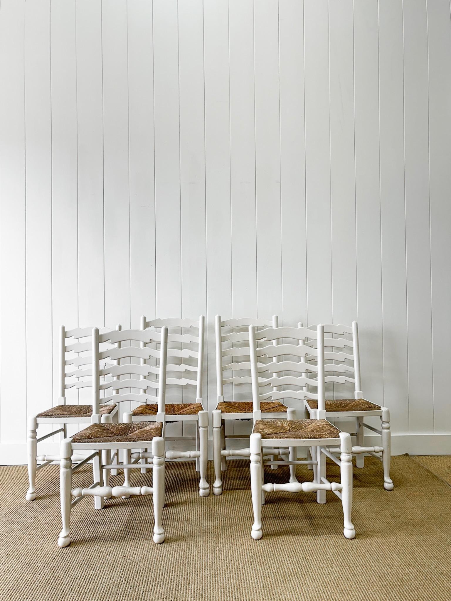 Ein hübscher Satz von sechs weiß lackierten englischen Leiterrückenstühlen mit schönen warmen Binsen-Sitzen. Zwei Stühle sind 