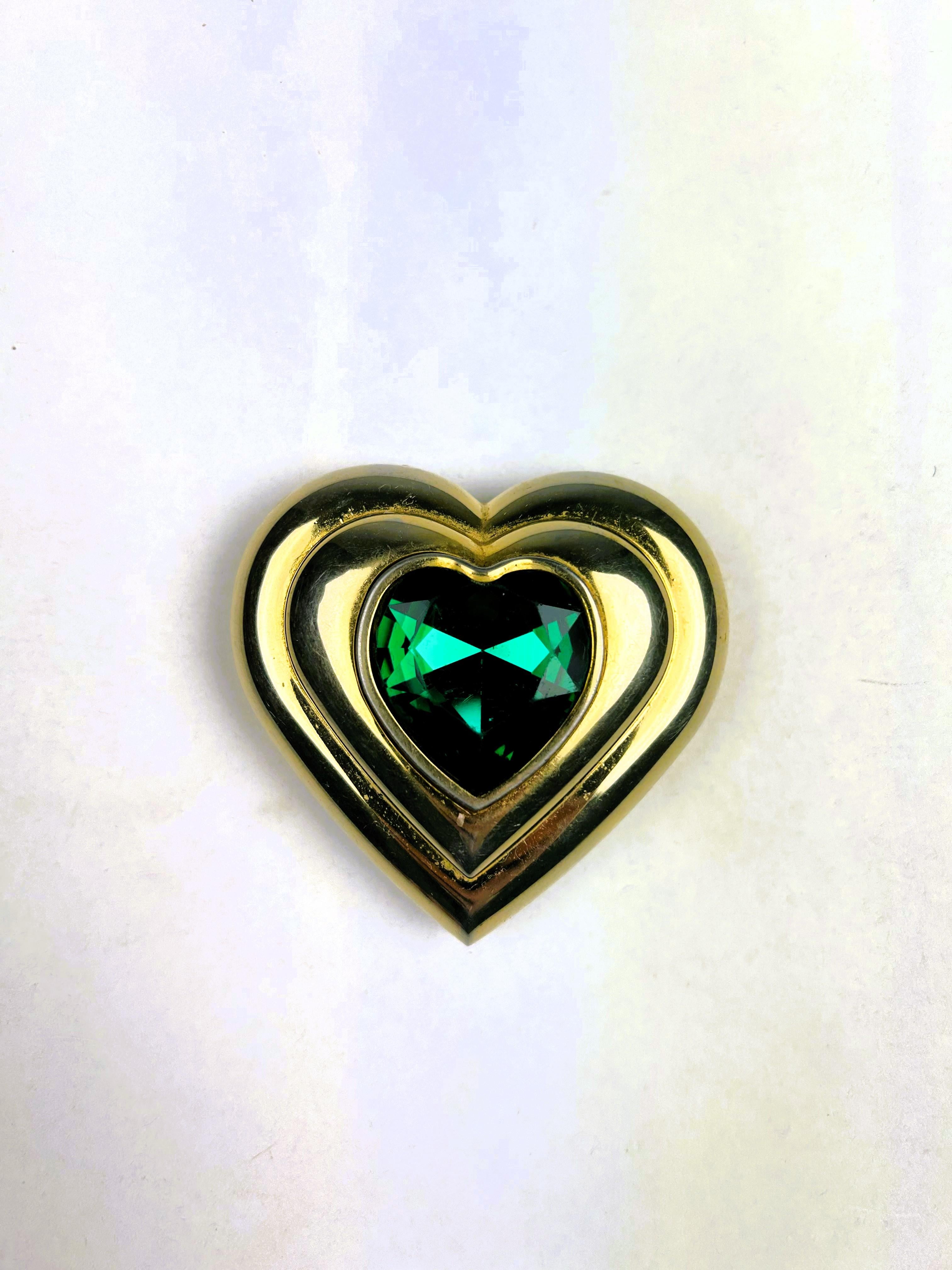Circa 1980. France

A vintage Yves Saint Laurent jewellery powder compact designed by Robert Goossens and dating from the 1980s. Heart-shaped in gold metal and emerald green crystal, this jewellery powder compact is compact and comes with its pink