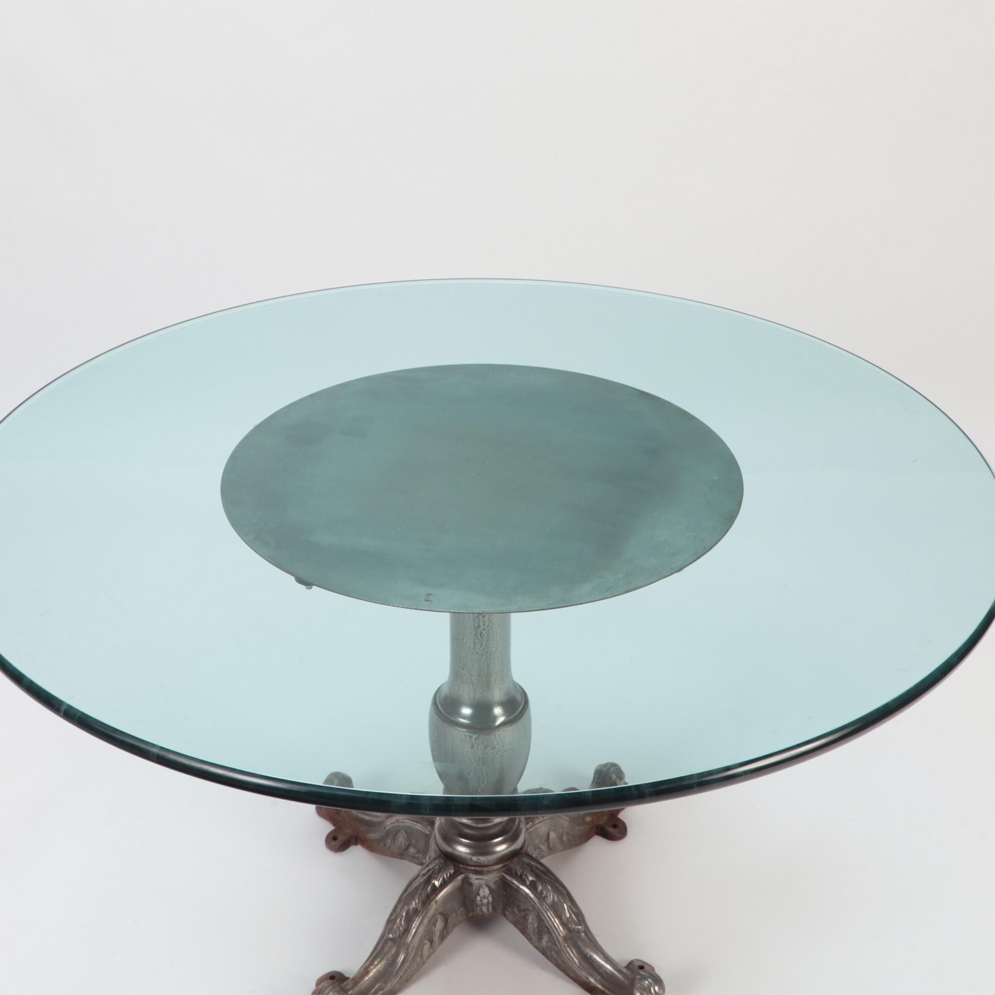 A heavy cast iron table with round glass top.