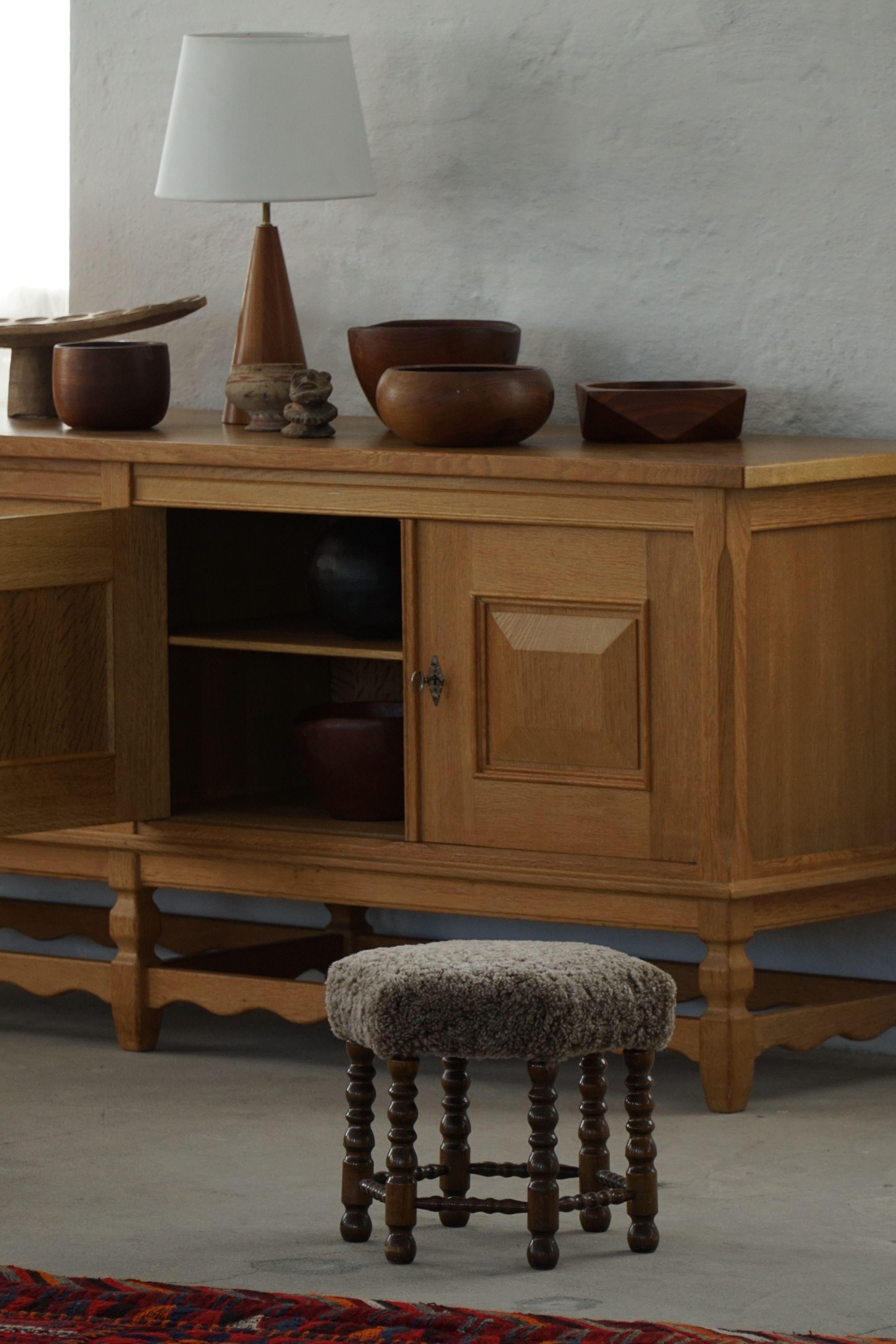 A Danish modern stool in oak, featuring distinctive curly legs and a hexagonal seat newly upholstered in high-quality dark grey lambswool. Crafted by a Danish cabinetmaker in the 1950s, this fine piece presents a refined yet inviting aesthetic. Its