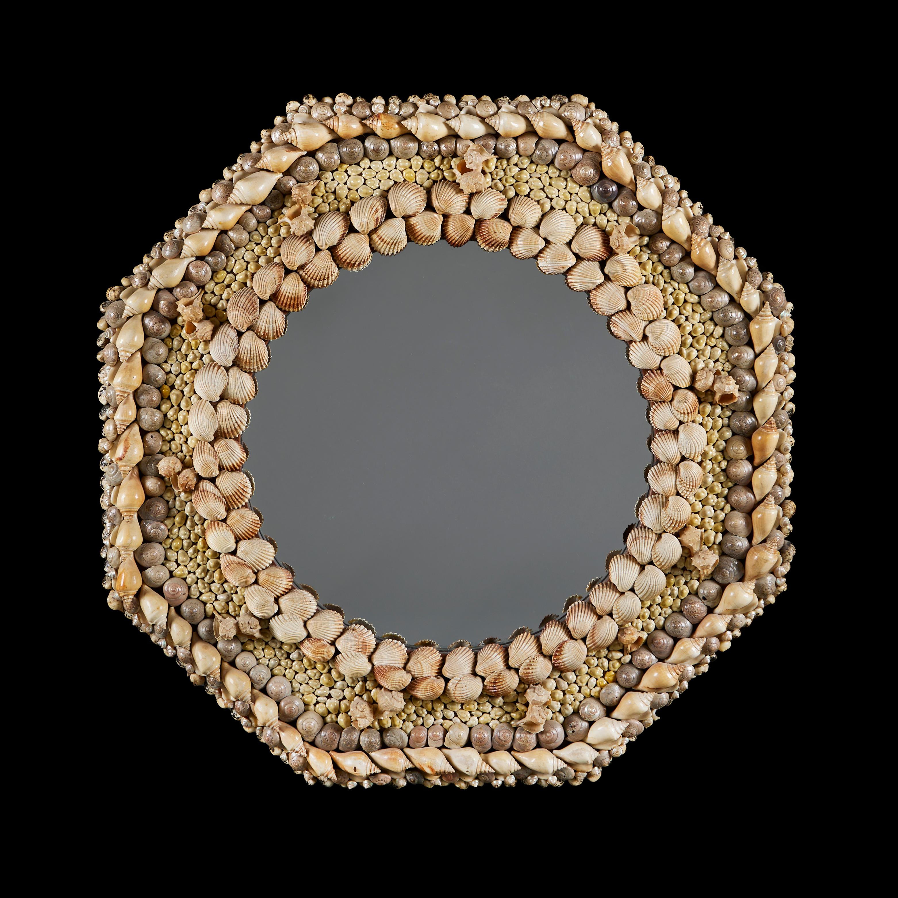 England, circa 1940
An unusual early twentieth century hexagonal mirror with shell decoration throughout, the whimsical shell frame surrounding a circular mirror plate. 

Height   74.00cm
Width    74.00cm