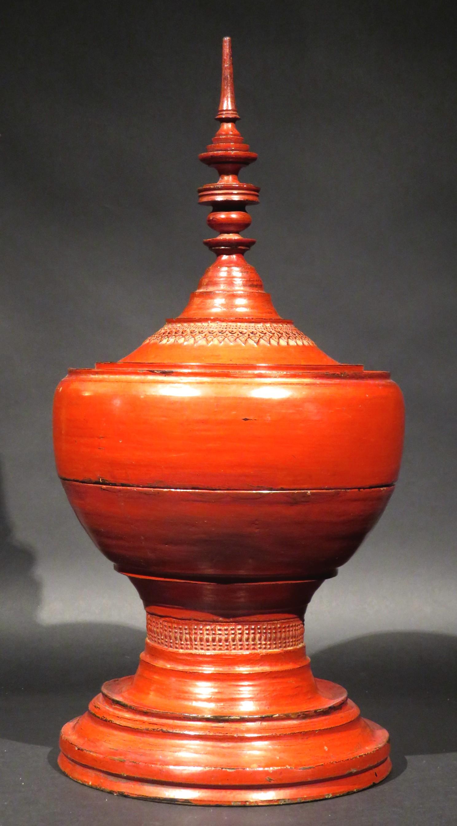 A highly decorative and visually striking antique Burmese (Myanmar) food container, constructed by hand using turned wood & bamboo, then hand carved and decorated overall in a striking vermillion red lacquer. 
These vessels were used to carry food