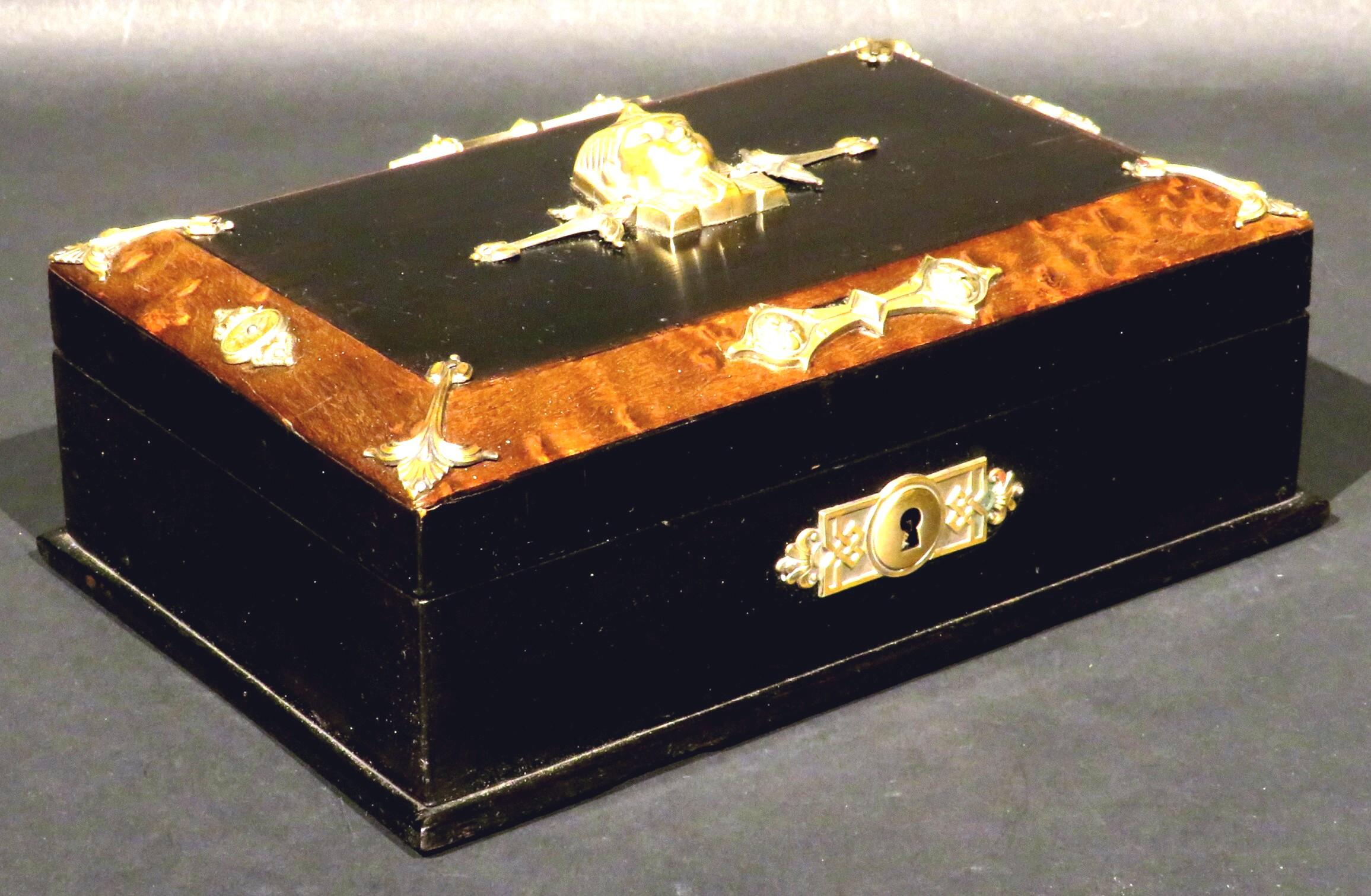 A highly decorative Egyptian Revival jewellery box or trinket box, the hinged & part ebonized lid featuring a finely detailed brass bust of an Egyptian Pharaoh, bordered within a burled & canted edge decorated with neoclassical brass appliques.