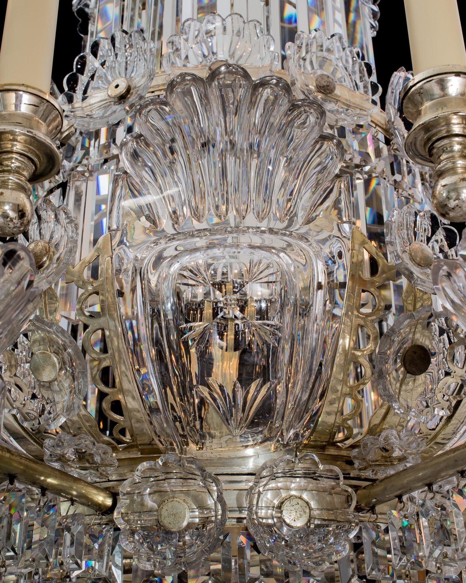 Eccezionale lampadario a 32 luci in argento montato e cristallo tagliato, sospeso da una grande tromba, quattro anelli concentrici con rosette di vetro appese a prismi a cascata, la cornice principale che racchiude otto pannelli di vetro tagliati