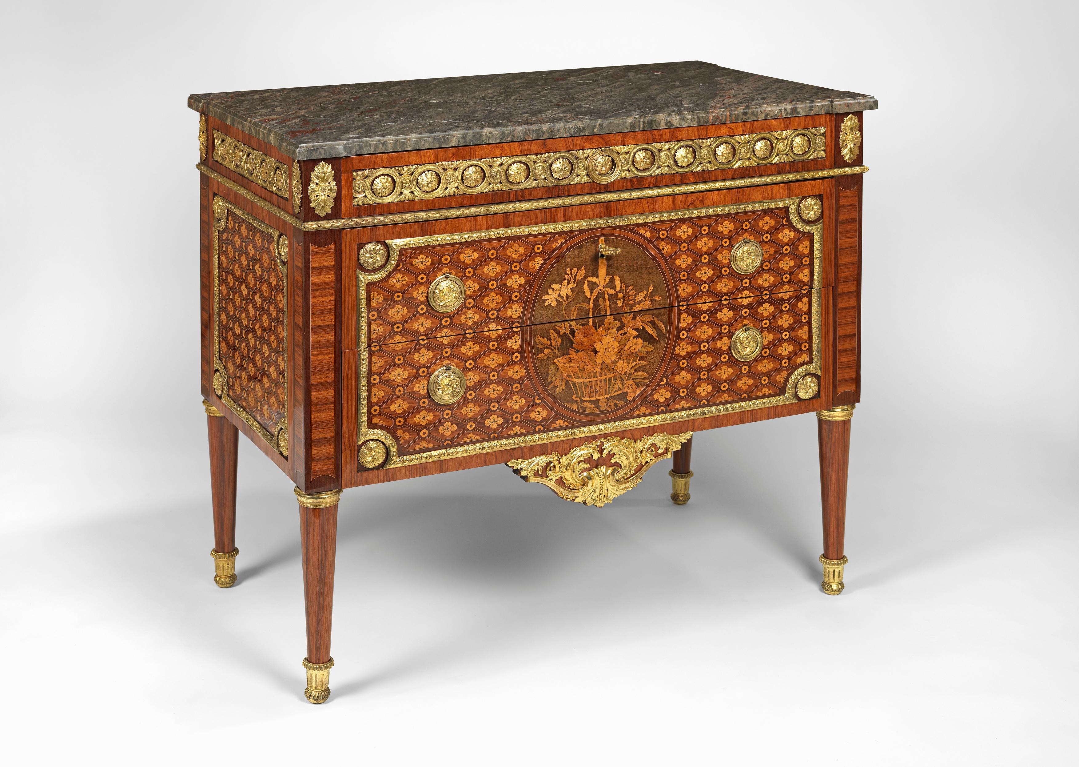 The commode having three drawers, the first set in the frieze, mounted with panels of ormolu interlace and rosettes above the remaining two drawers. These doors are inlaid with flower heads and interlacing within a geometrical pattern and set within