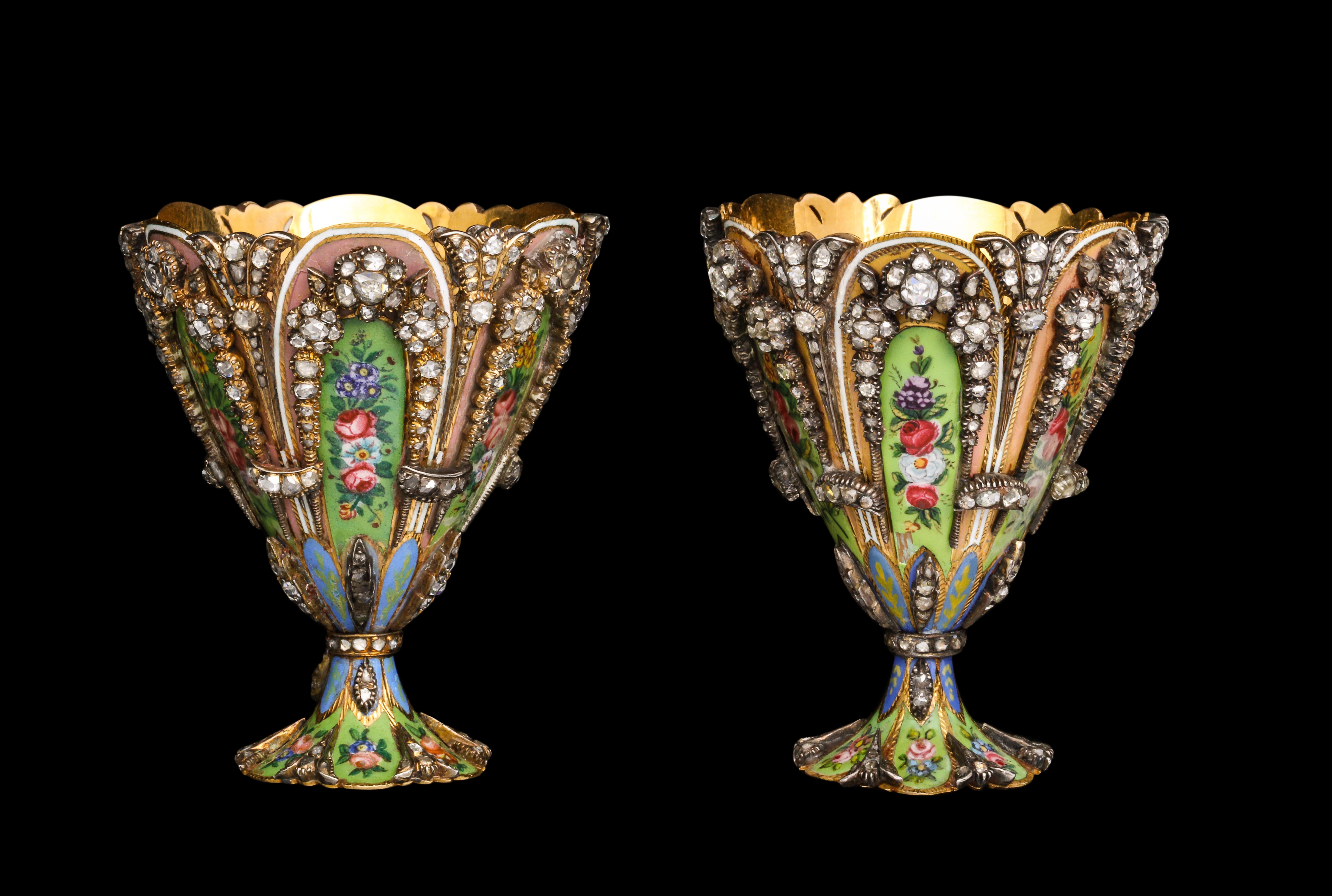 A Highly Important Museum Quality Pair of Diamond and Enamel Zarfs.

Each Zarf with  a scalloped rim and spreading foot, the sides set with colorful green and pink enamel plaques depicting flower heads and foliage. The stem and the base is a similar