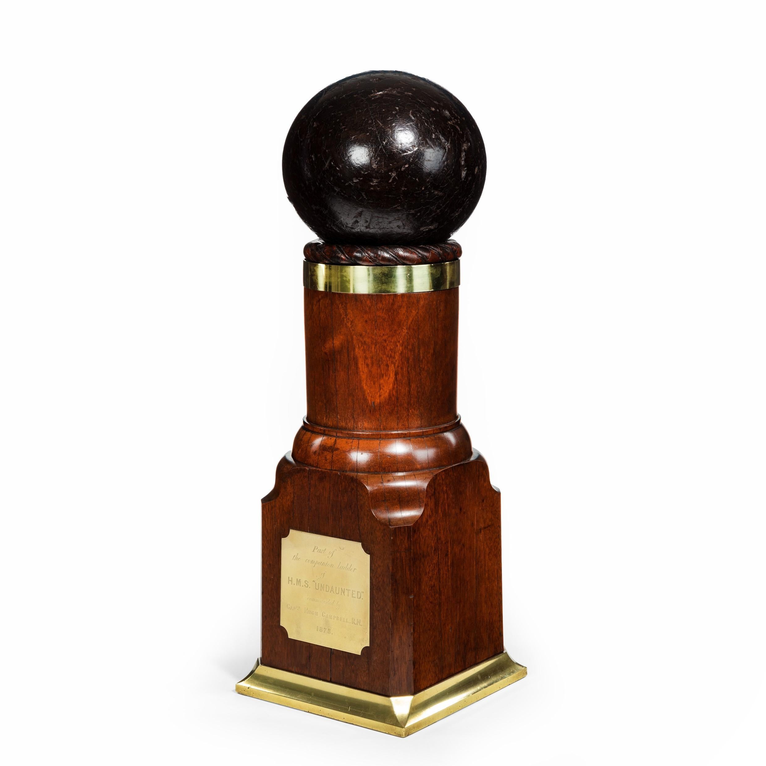 A H.M.S. Undaunted presentation souvenir for Captain Hugh Campbell RN, 1875, comprising part of a ladder post with a square section base and truncated cylindrical shaft capped with a rope-twist collar supporting a wooden ‘dummy’ cannon ball, with a