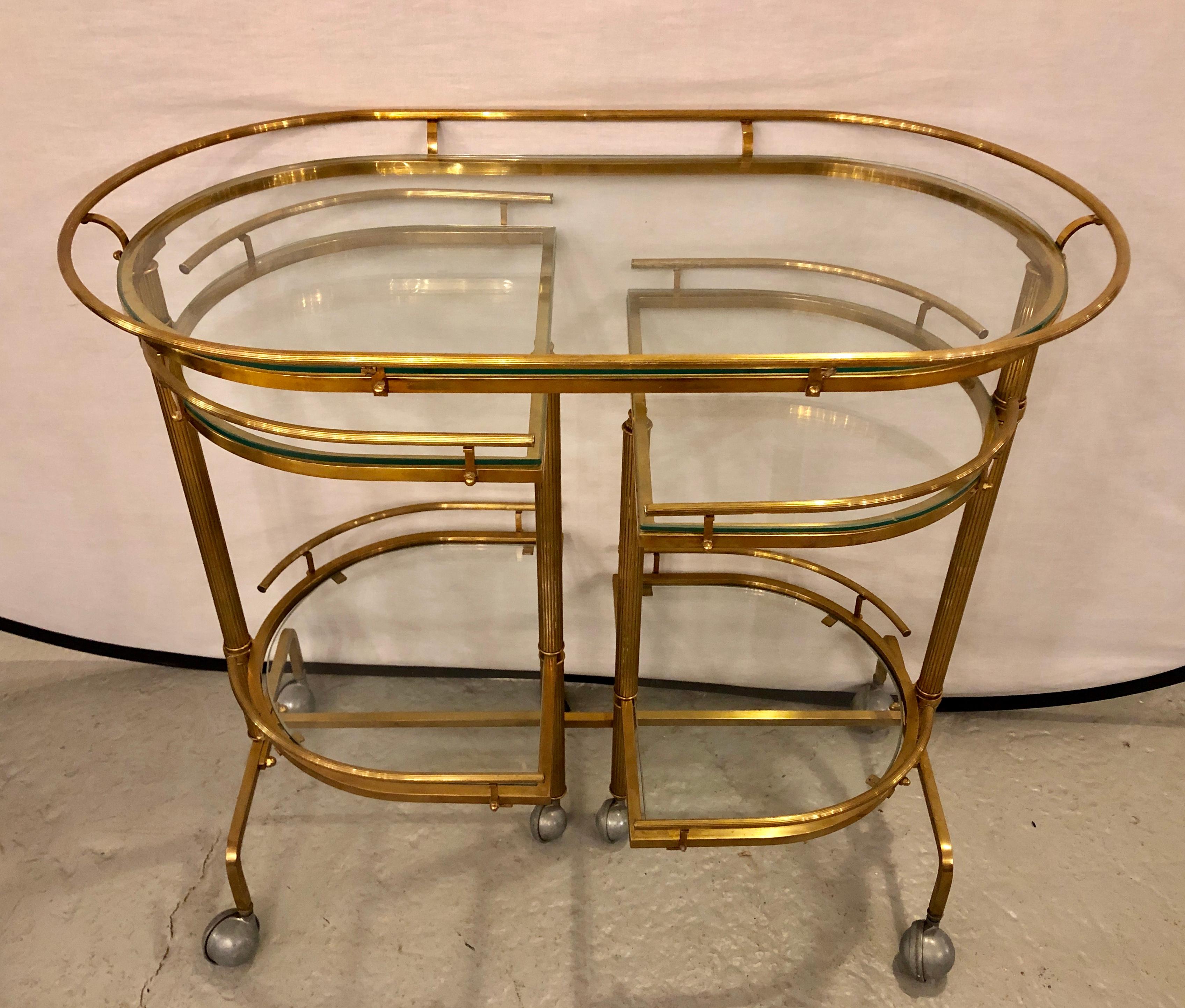 Hollywood Regency brass and glass swivel bar cart. This finely constructed rolling bar cart flows easily on it large casters with swing out side. The fully extended cart measures some 56 inches wide with a pair of lower and upper trays flanking a