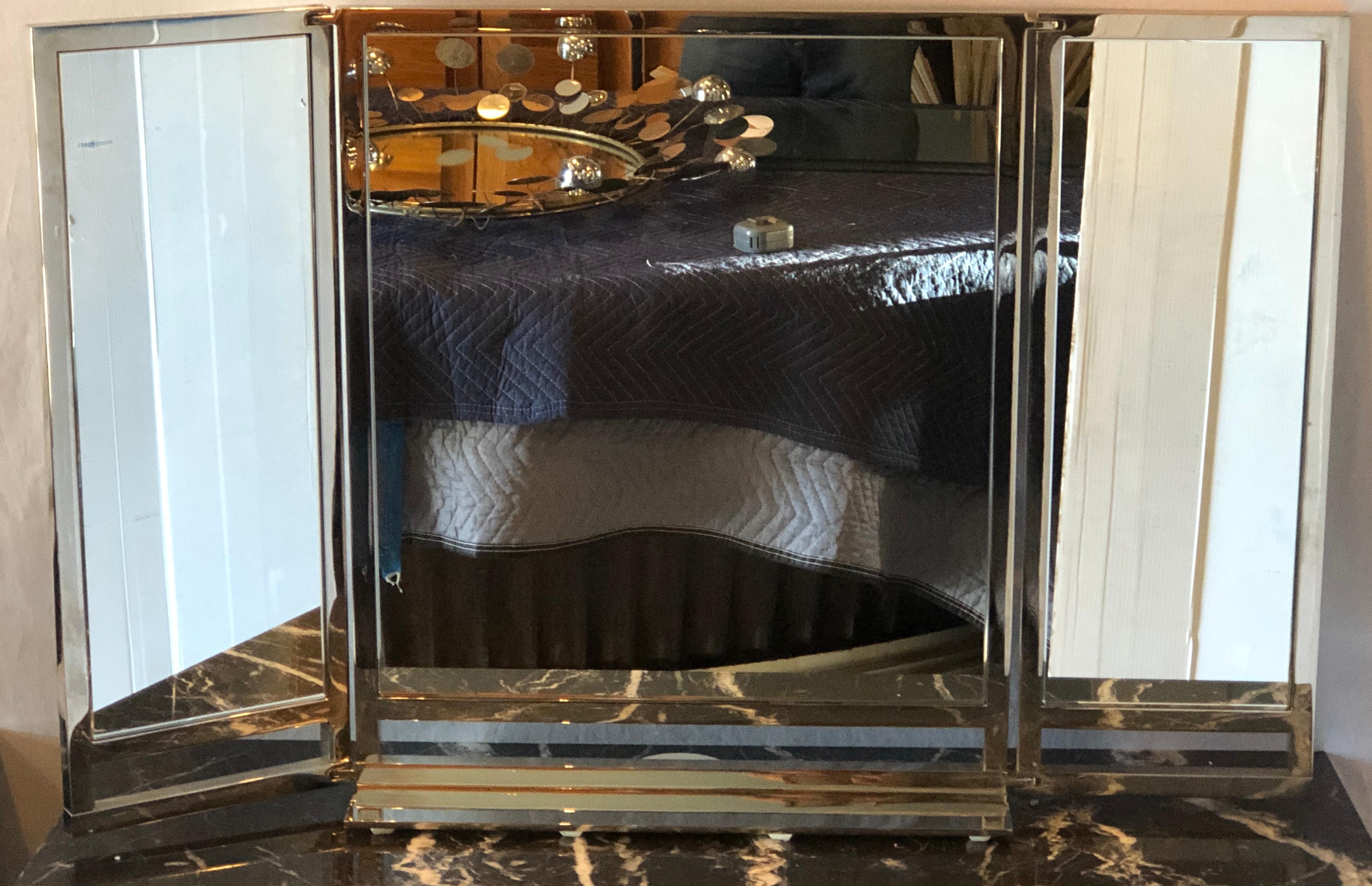 A Hollywood Regency style solid heavy chrome-plated tri-fold vanity or table mirror. The sleek and stylish design stands out as this is certain a designer or decorator piece. The floating base supporting three mirror panels all framed in chrome. Too