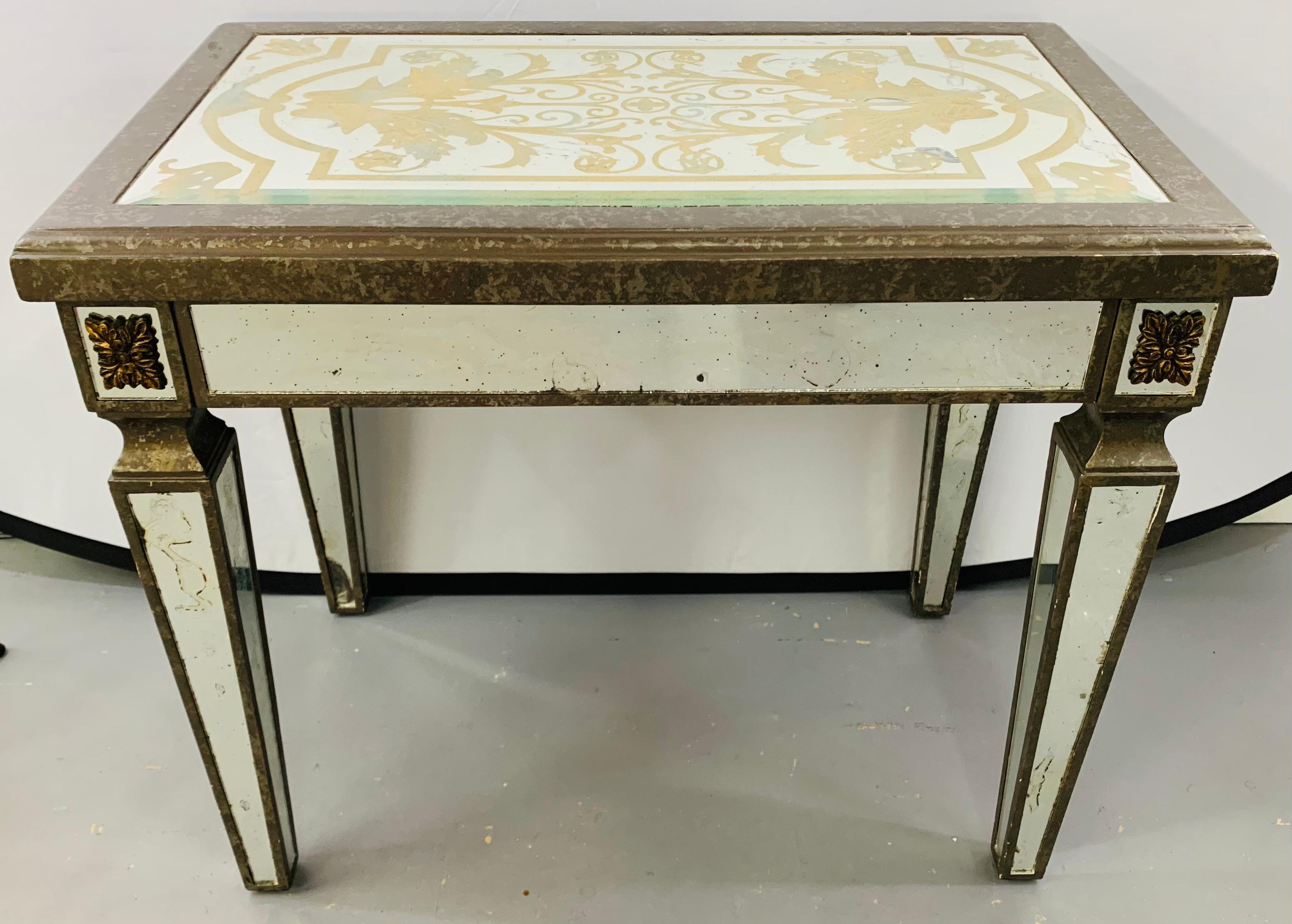 A Hollywood Regency style églomisé mirrored side table. The table top features a fine gold yellow paint design with a wooden antiqued frame. The fluted legs are elegant and also mirrored in an antiqued fashion.

There is a small damage to the top