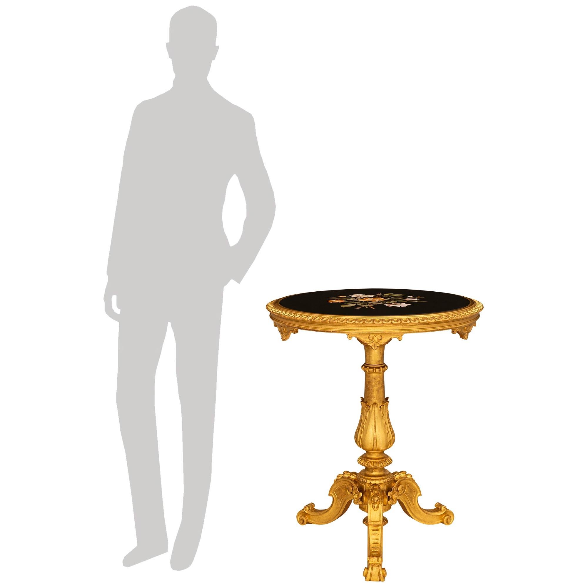 Superbe et très décorative table d'appoint en bois doré et marbre Pietra Dura de style Florentine du XIXe siècle. La table repose sur trois pieds à enroulements, avec des enroulements inférieurs et des vignes de laurier finement sculptées au sommet.