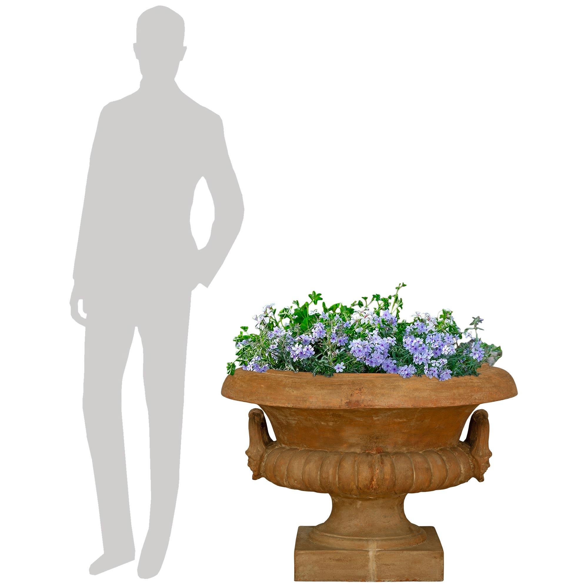 Une belle et très décorative urne/plante en terre cuite italienne du 19e siècle. La grande jardinière romaine est surélevée par une fine base carrée au-dessous du socle légèrement incurvé en forme de piédestal. La partie supérieure du corps présente